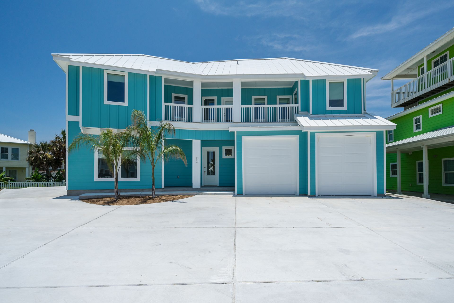 A blue and white house with two garages and a white driveway