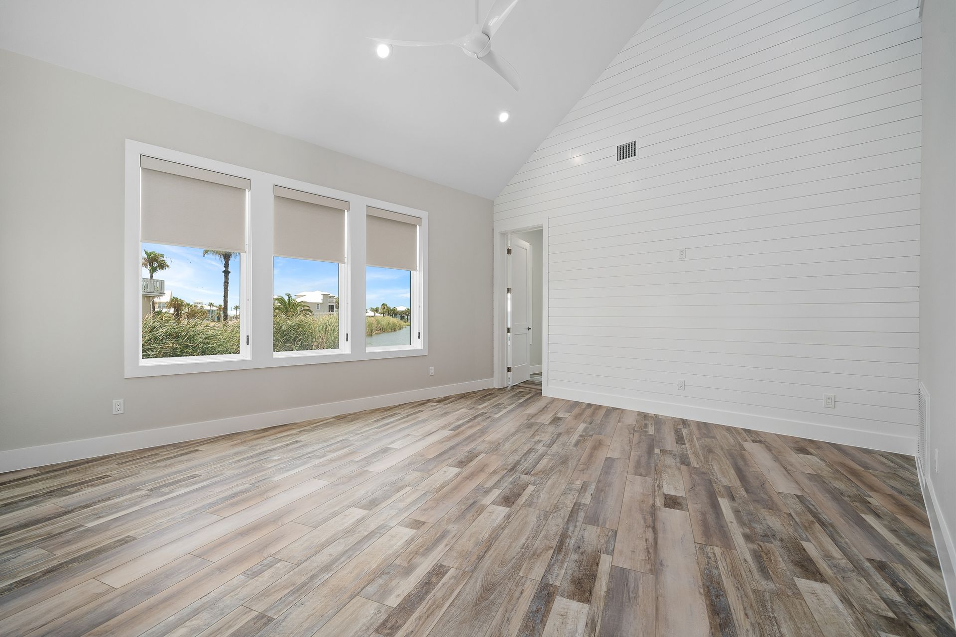 A large empty room with hardwood floors and three windows.