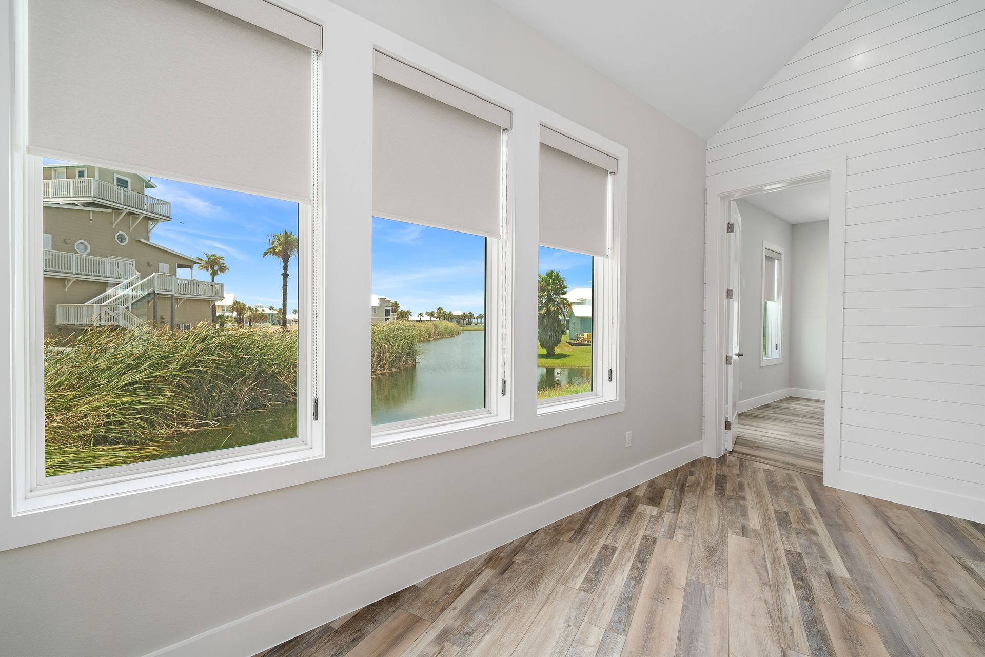 An empty room with three windows and a wooden floor.