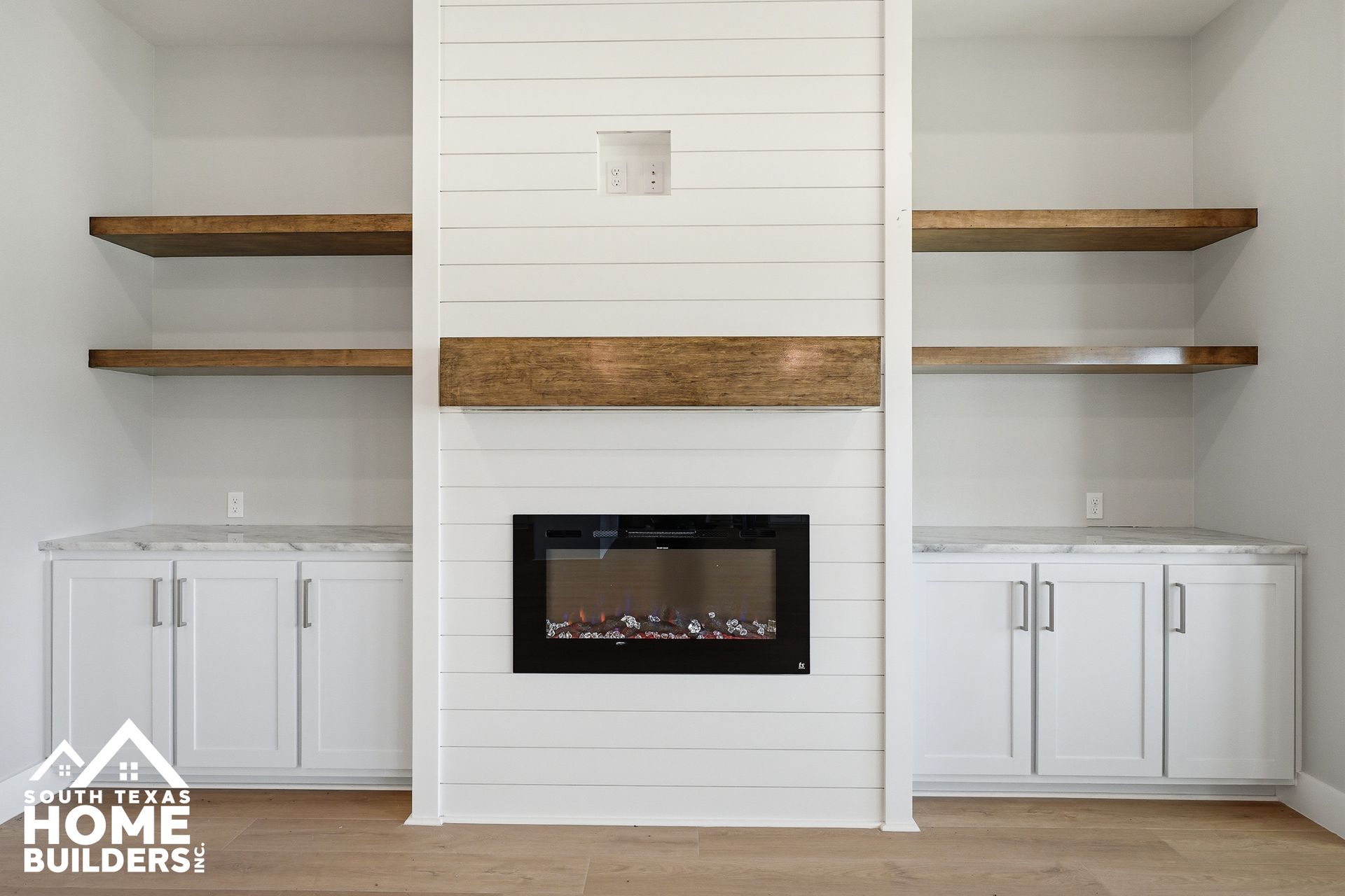 Modern fireplace with white shiplap, wood mantel, built-in cabinets, and open shelves on both sides