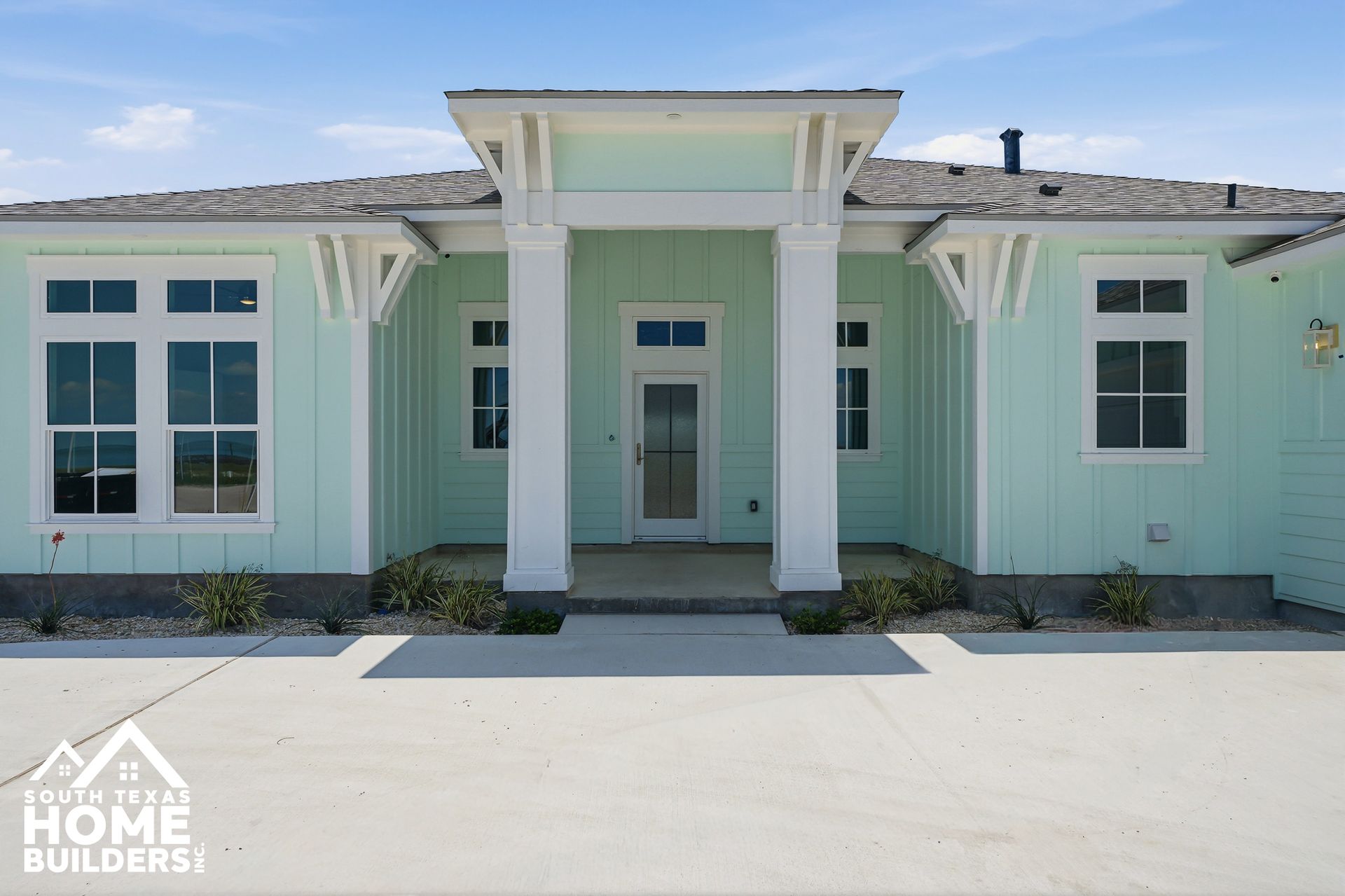 Mint-green modern house exterior with white trim and large windows, centered front entry.