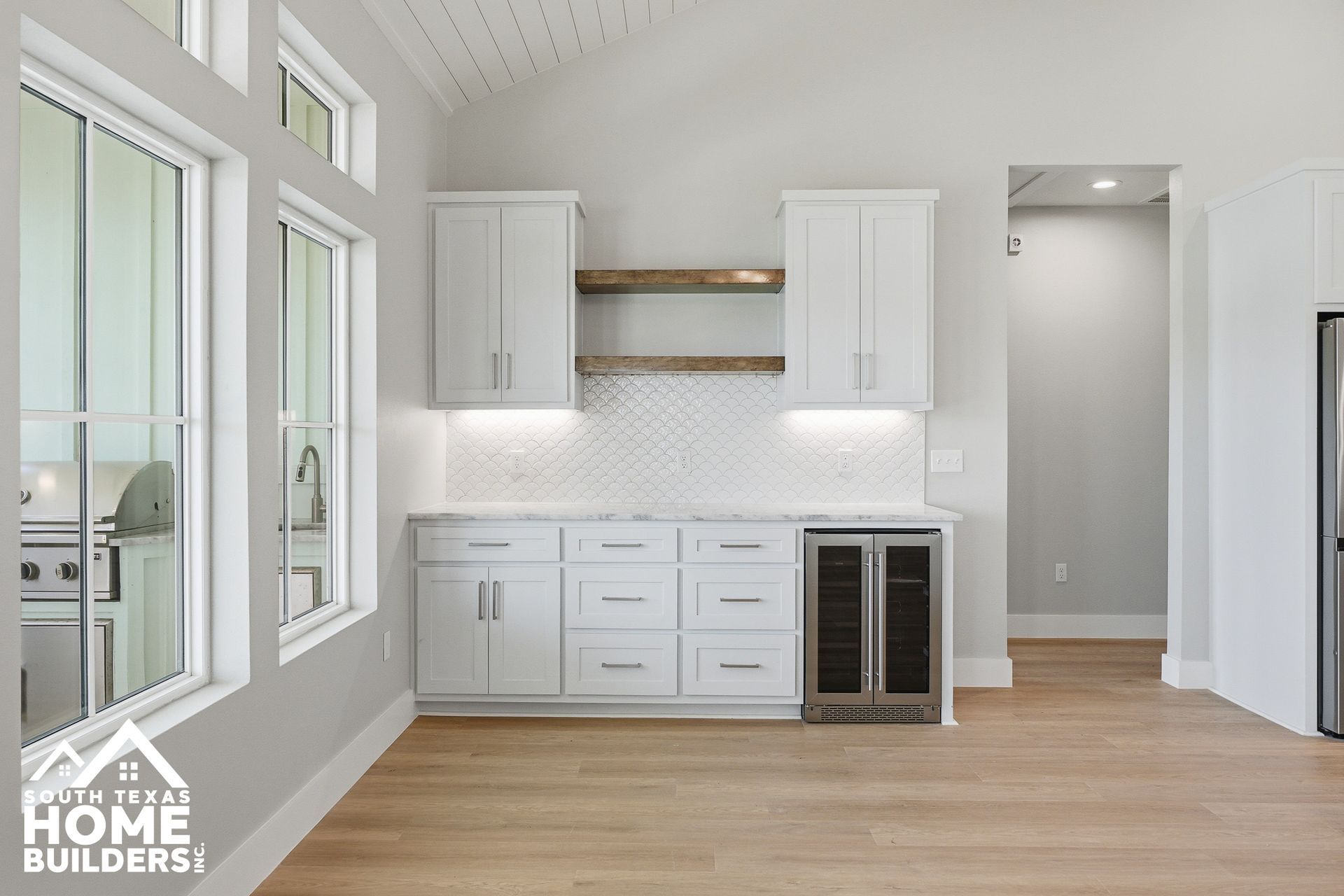 Bright modern kitchen with white cabinets, open shelves, and wood floors