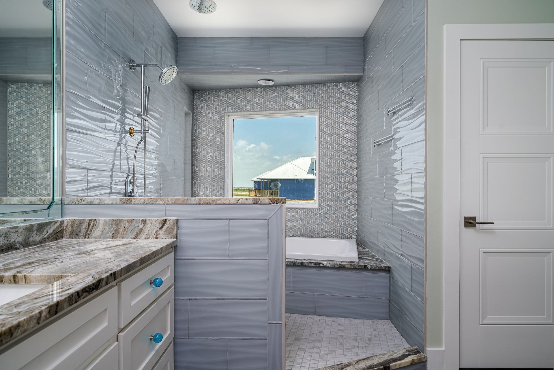 A bathroom with a tub , sink , mirror and window.