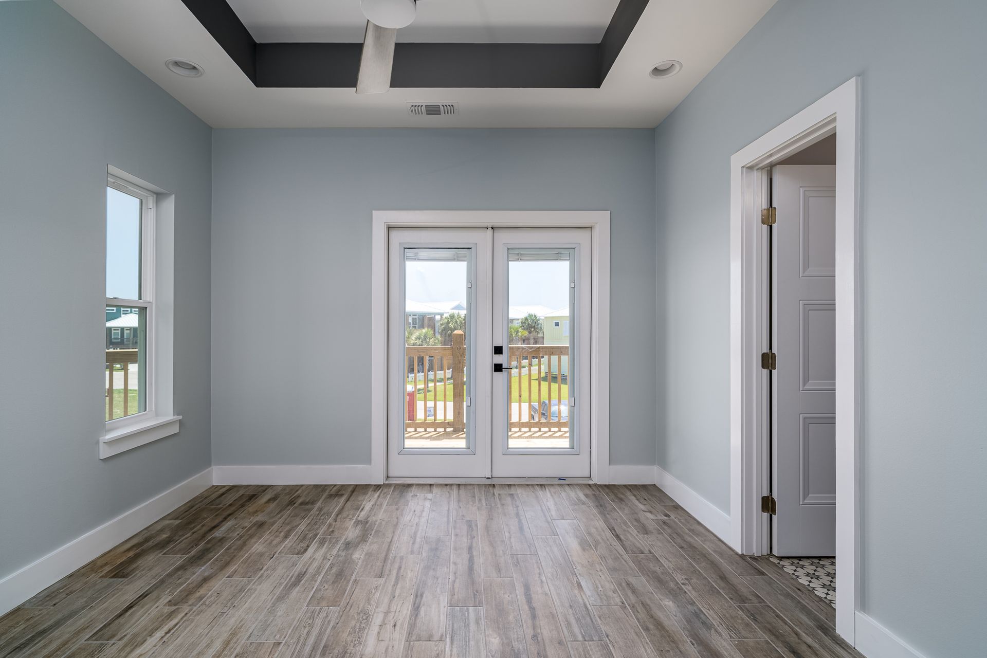 An empty room with a balcony and sliding glass doors.