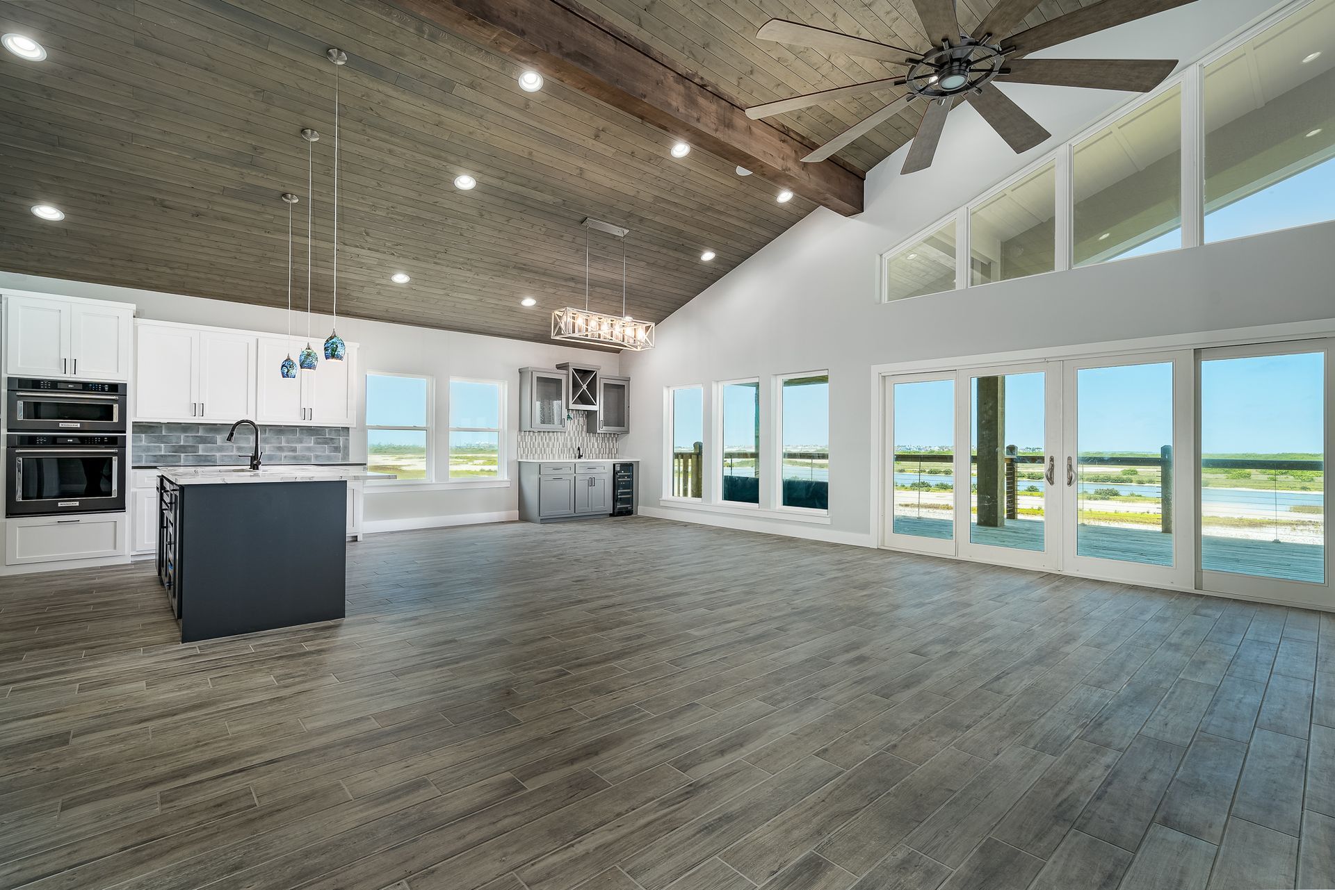 An empty kitchen with a ceiling fan and lots of windows