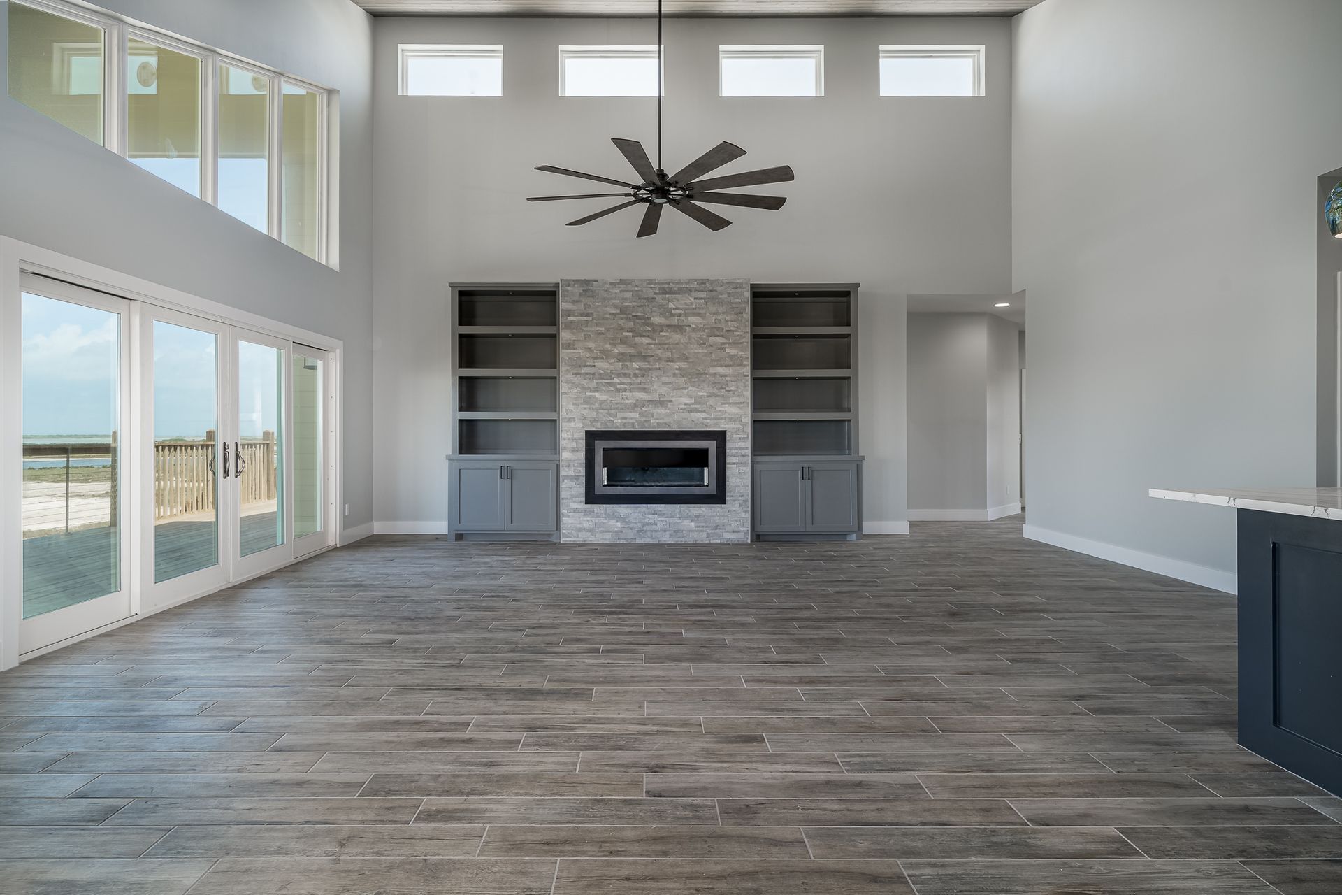 An empty living room with a fireplace and a ceiling fan