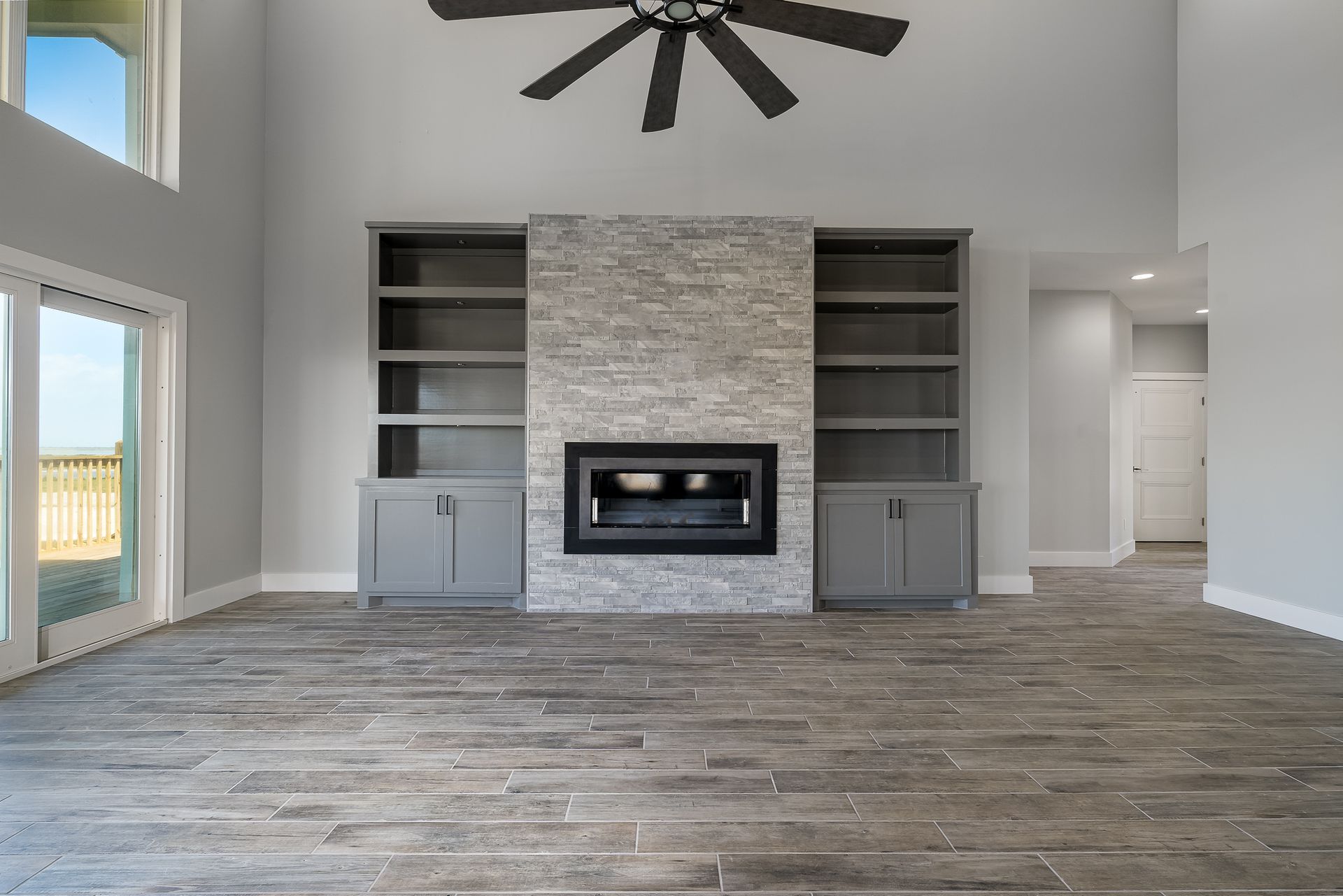 An empty living room with a fireplace and a ceiling fan.