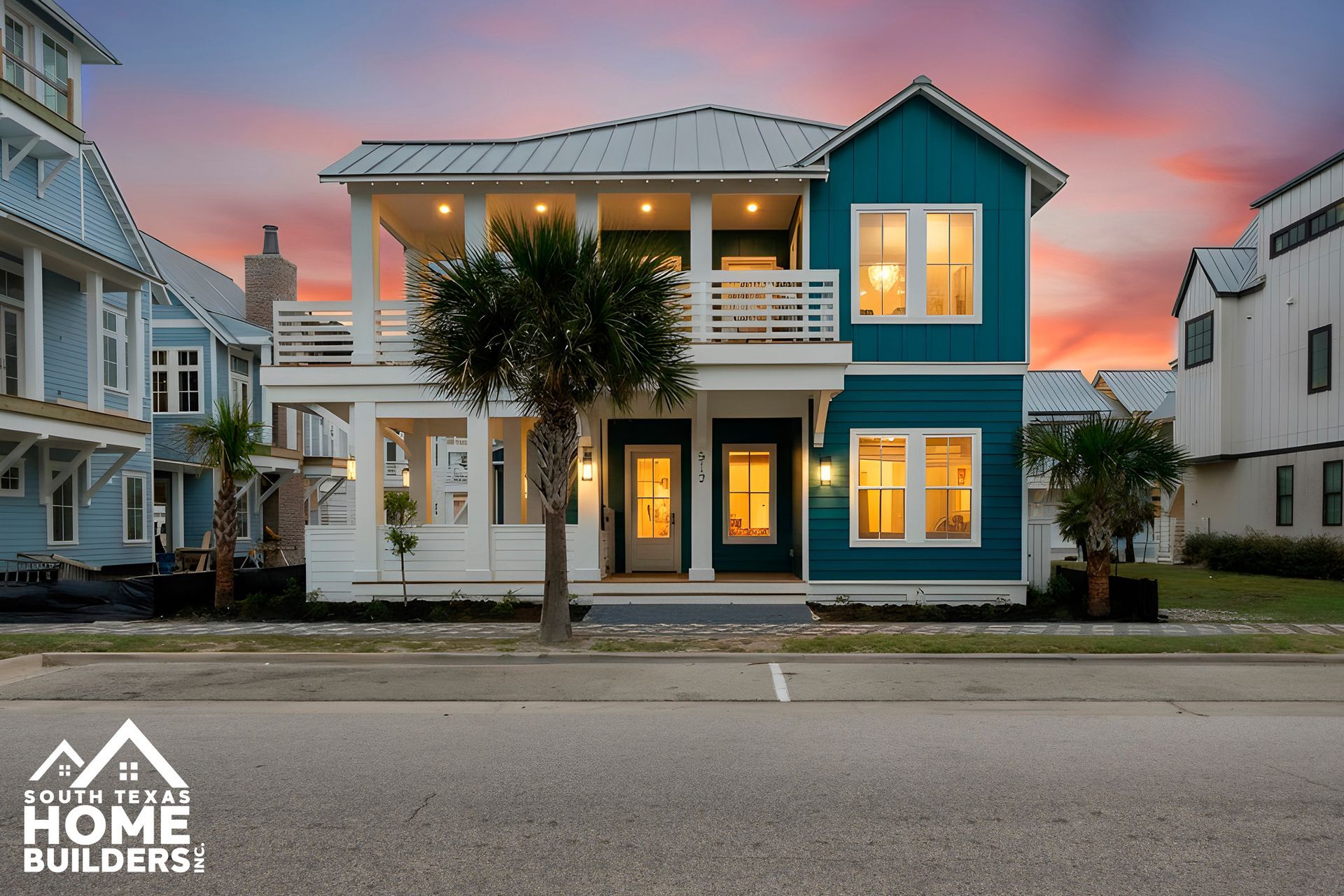 Two-story teal house with white trim and balconies, next to a street. Palm tree in front.