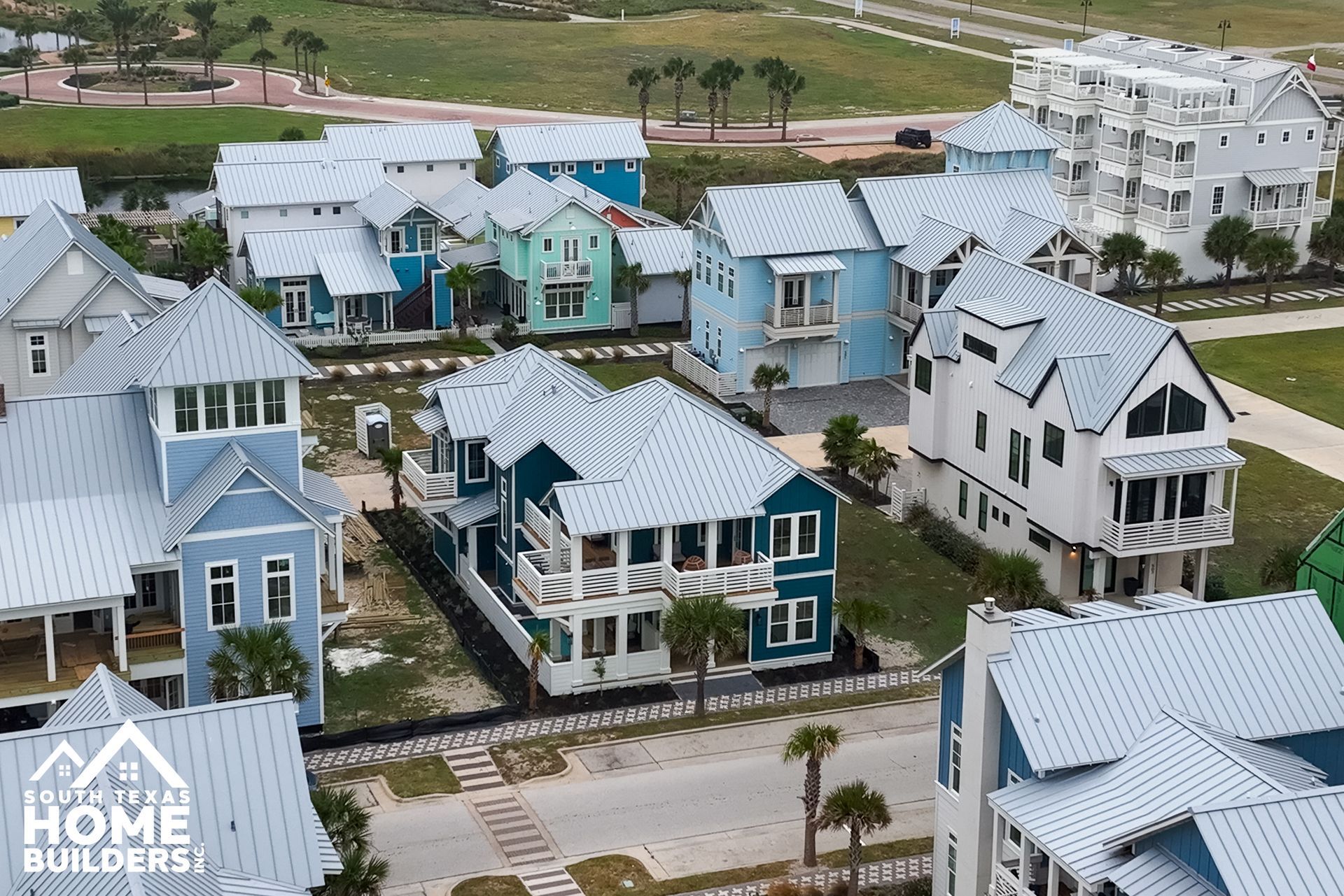Aerial view of a coastal neighborhood with colorful houses and silver roofs.