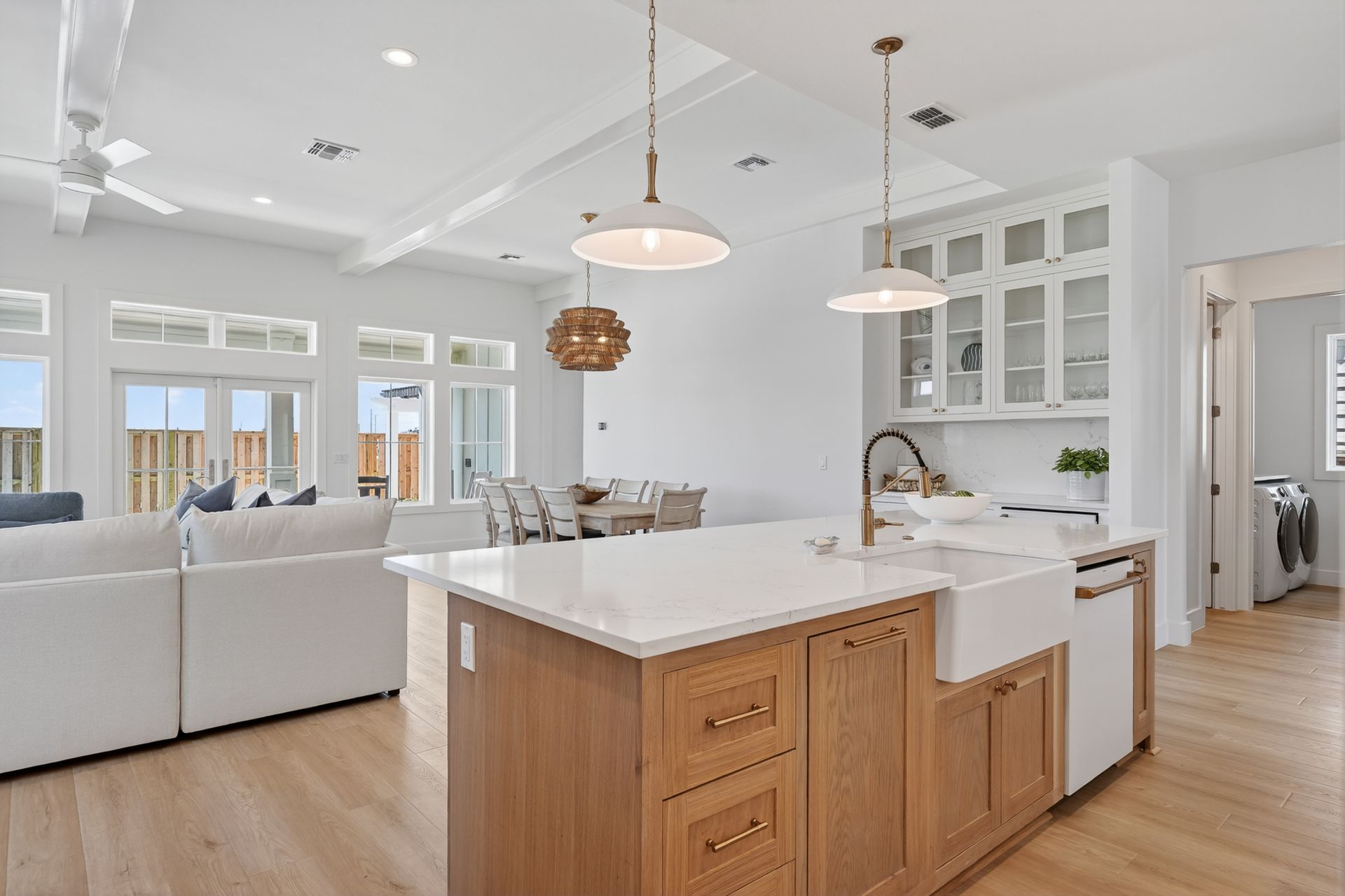 Bright open kitchen with white island, wood cabinets, and adjoining living room with hardwood floors