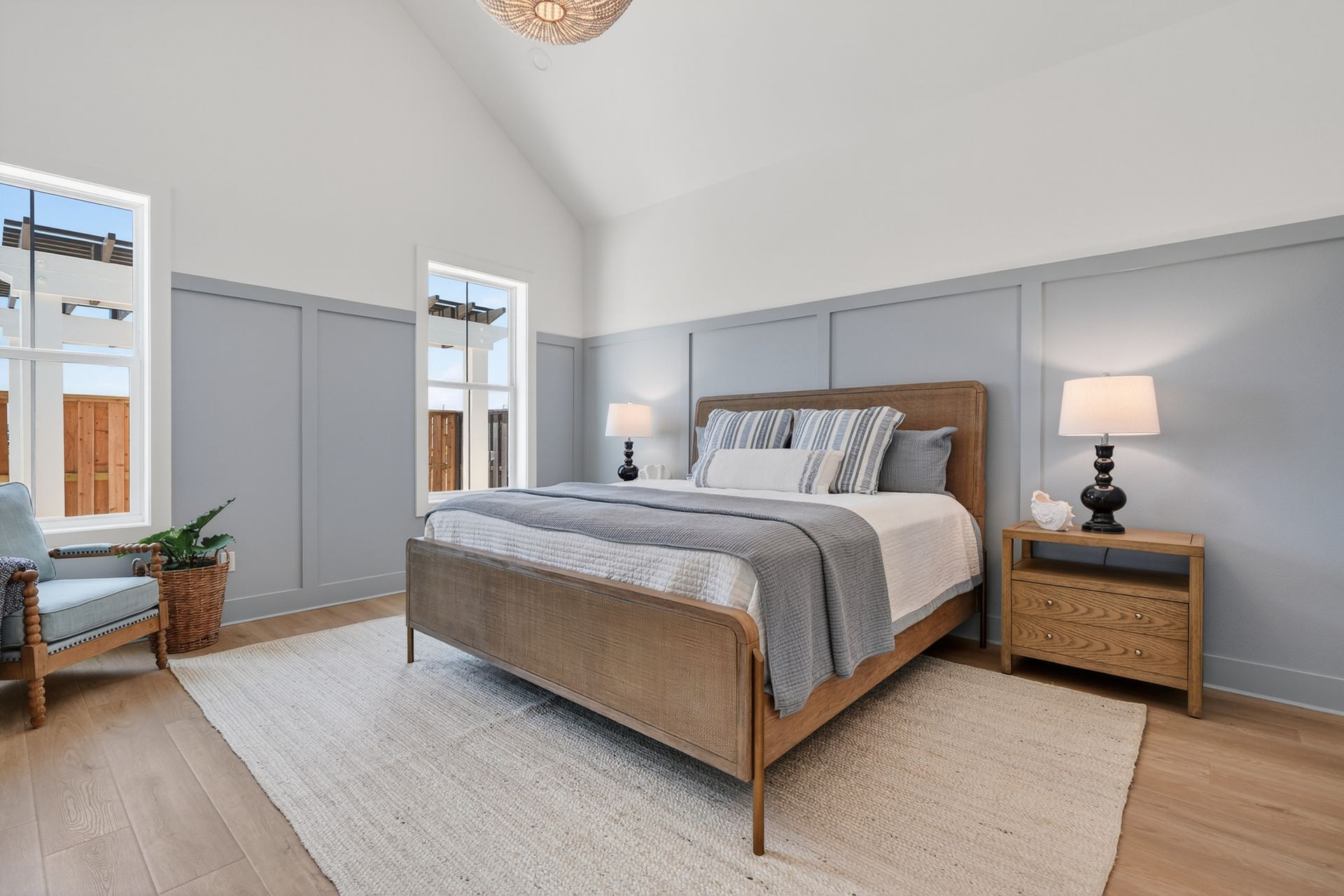 Bright bedroom with a wood bed, gray accents, bedside lamps, wardrobe, and soft beige rug