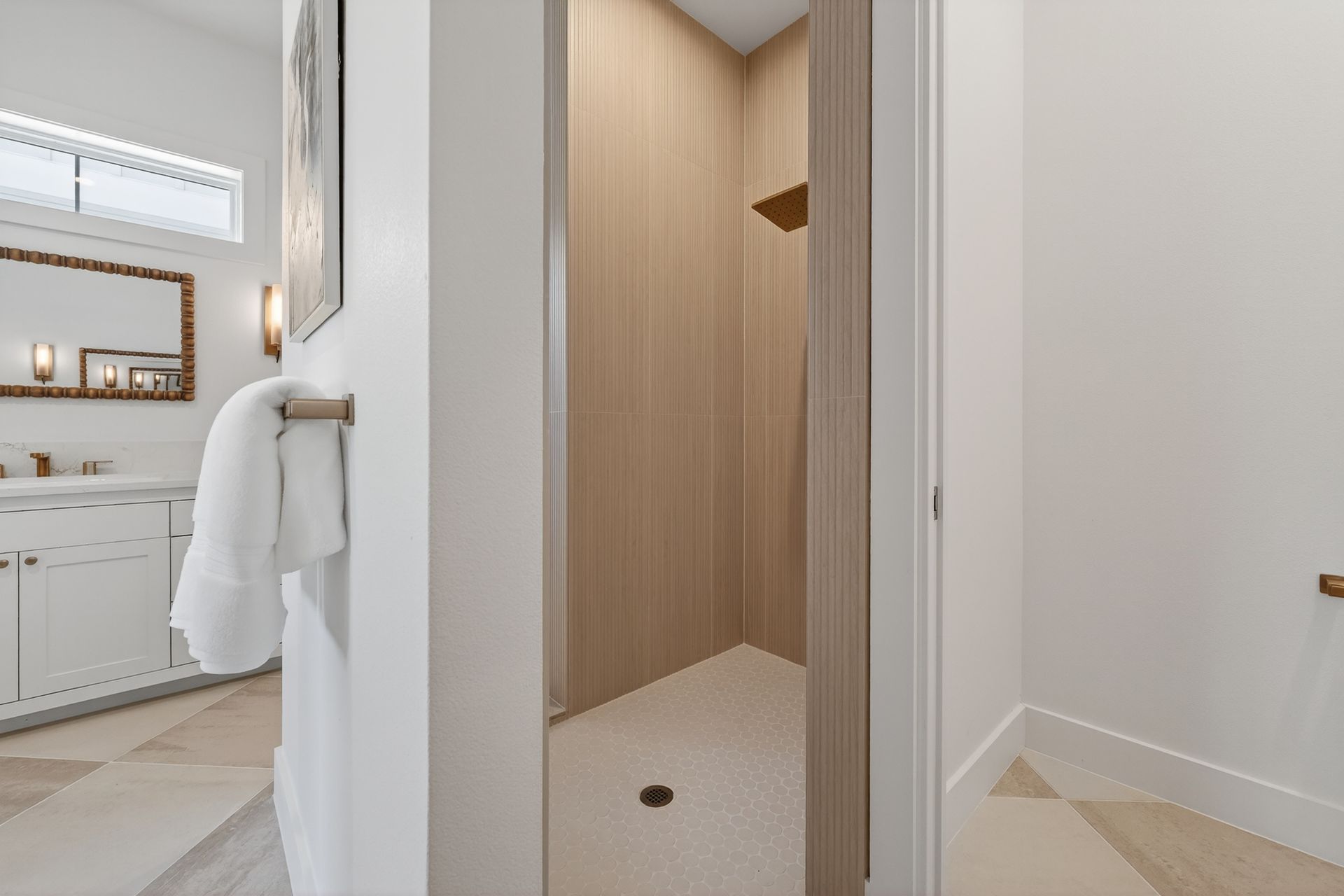 White bathroom hall with wood-paneled shower entry, towel hook, vanity, and tiled floor