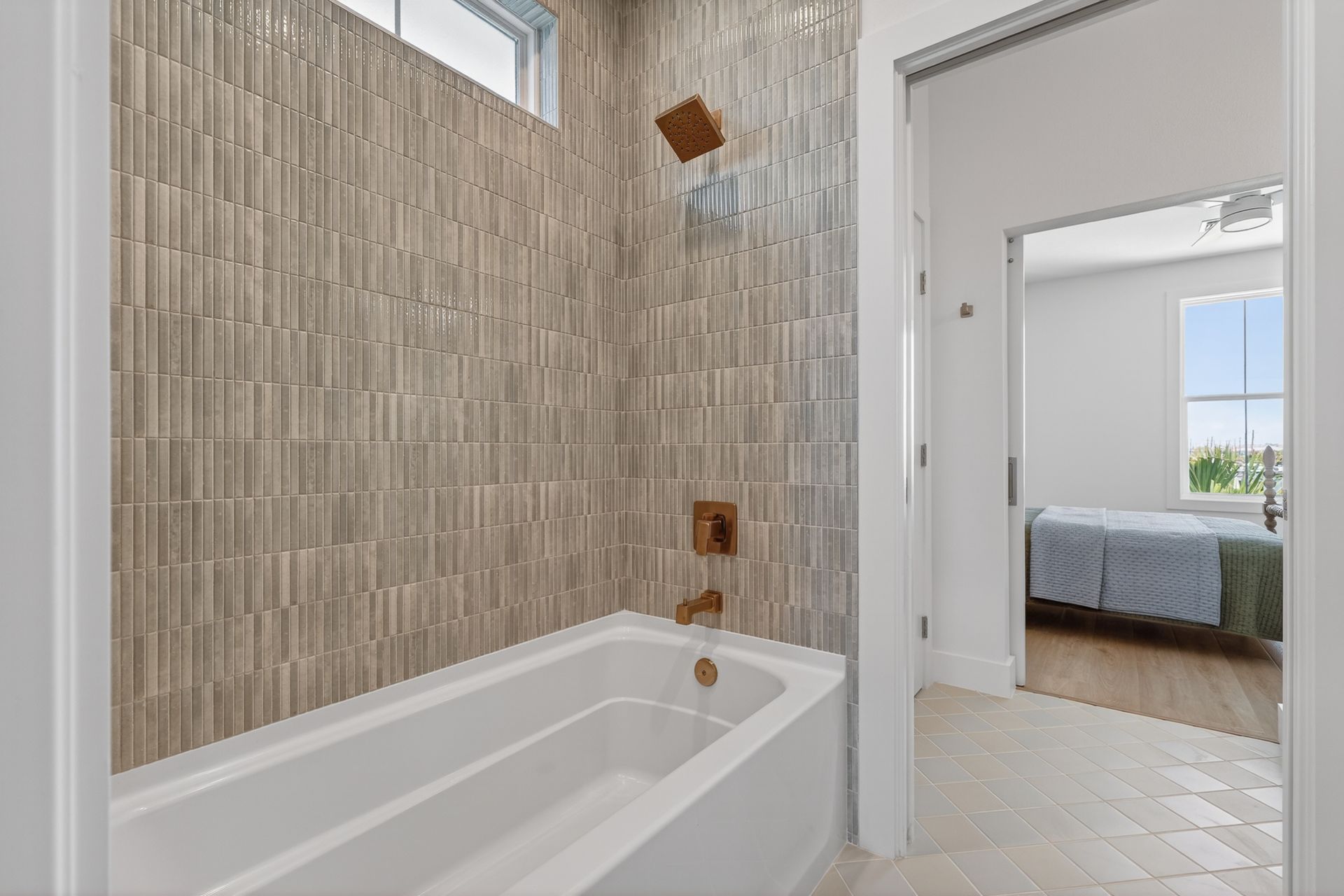 Modern bathroom with tiled shower-tub and open doorway to a bright bedroom