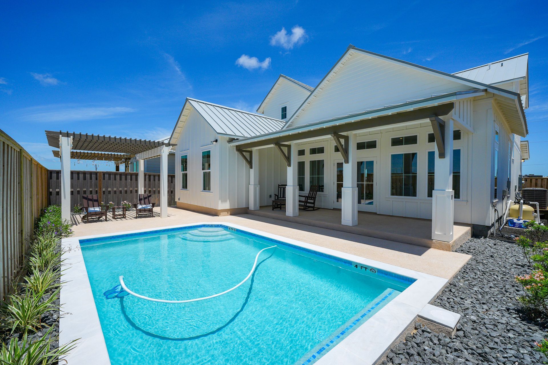 Modern white house with a bright blue pool and patio under a clear sky