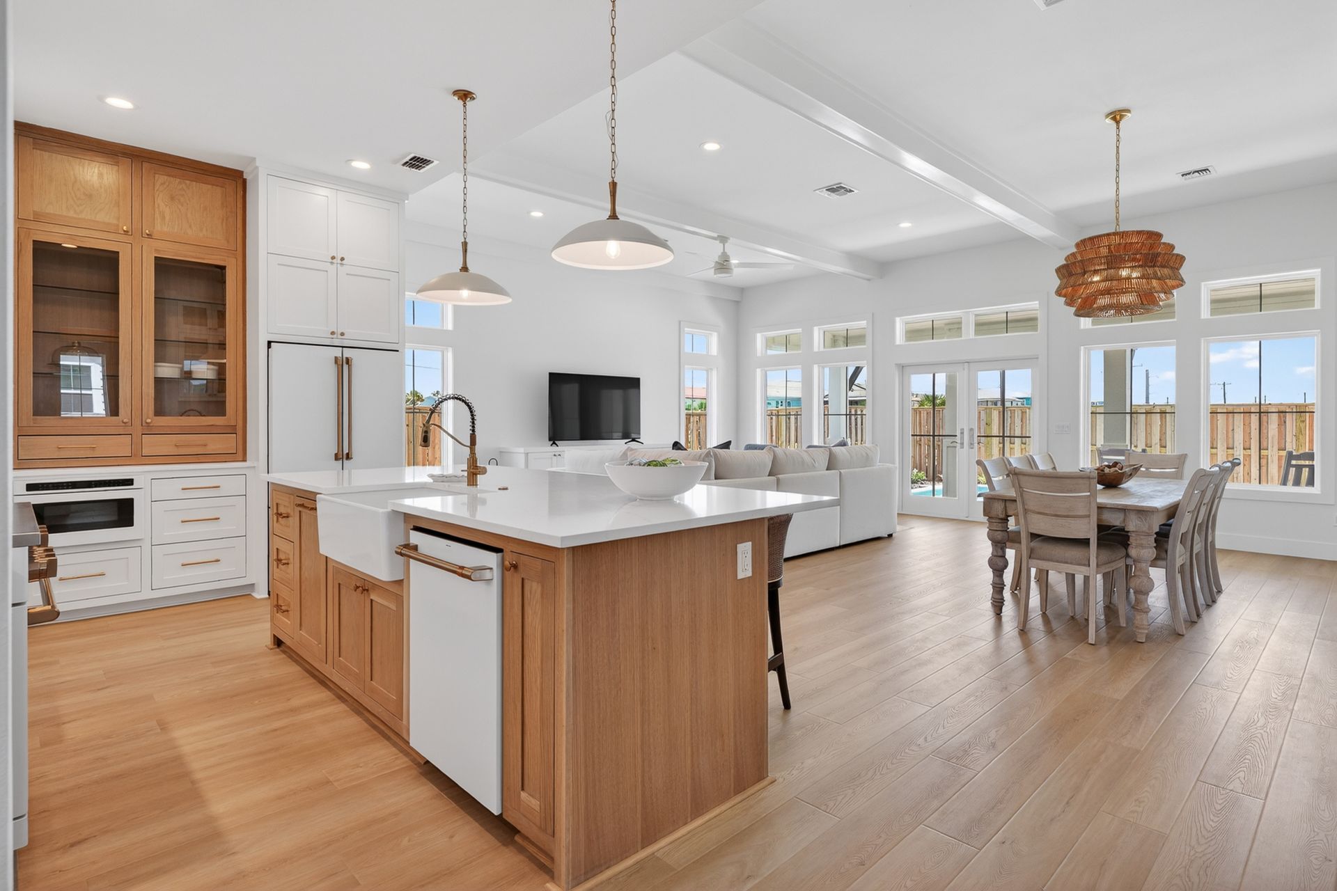 Bright open kitchen and dining area with white cabinets, wood floors, island, and large windows