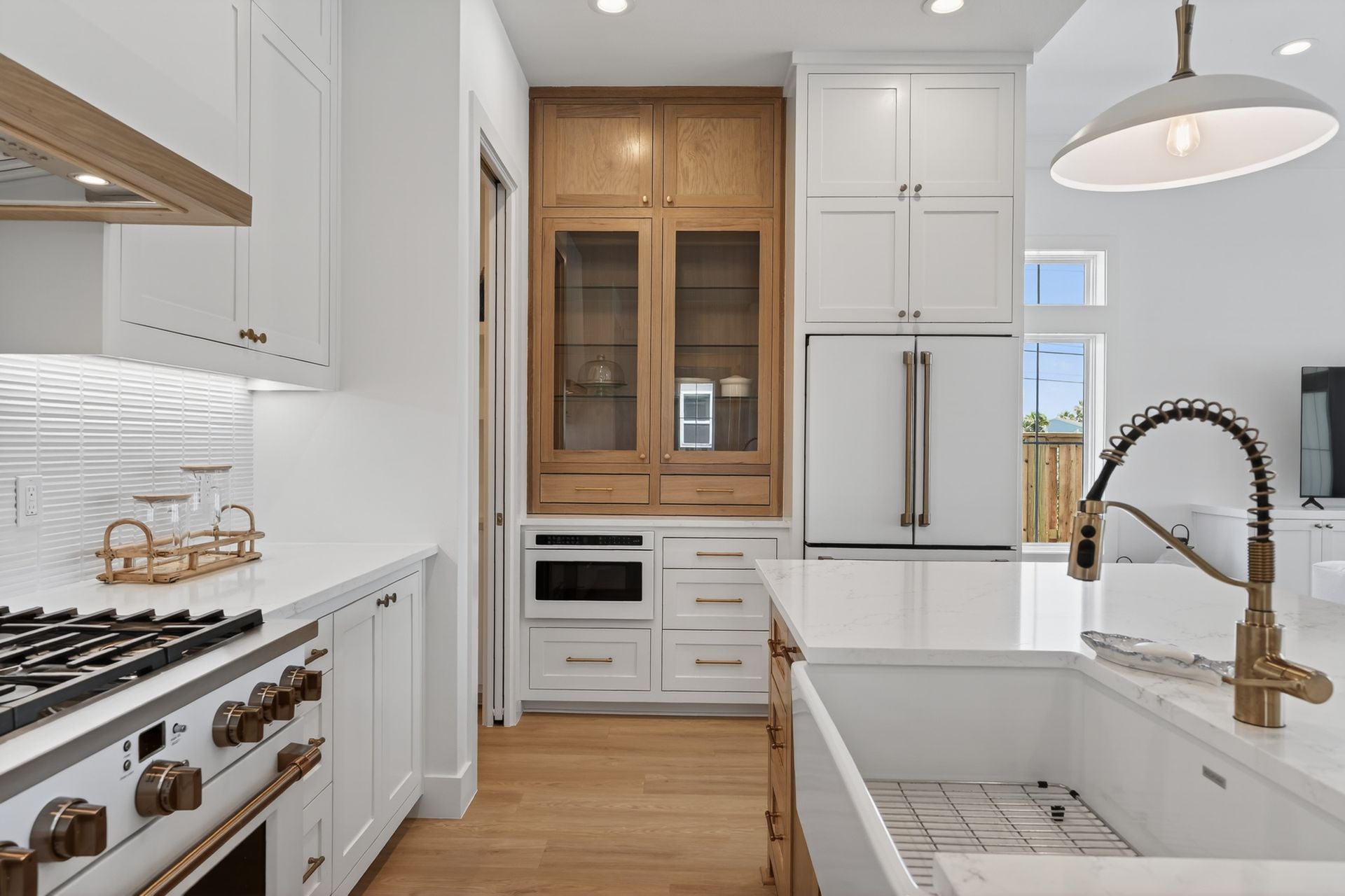 Bright white kitchen with wood cabinets, farmhouse sink, and stainless steel appliances