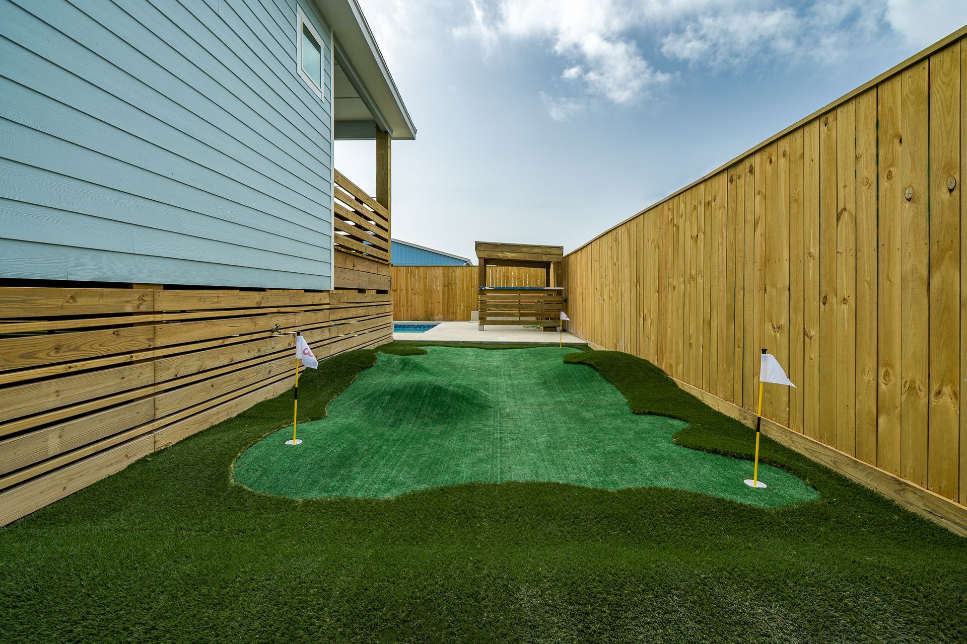There is a small golf course in the backyard of a house.