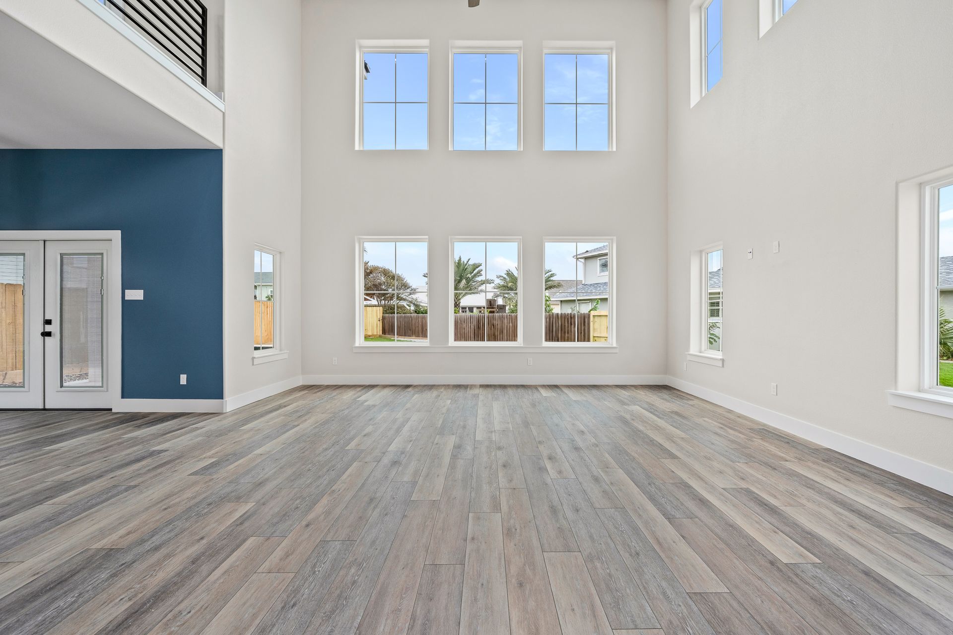 An empty living room with hardwood floors and lots of windows.