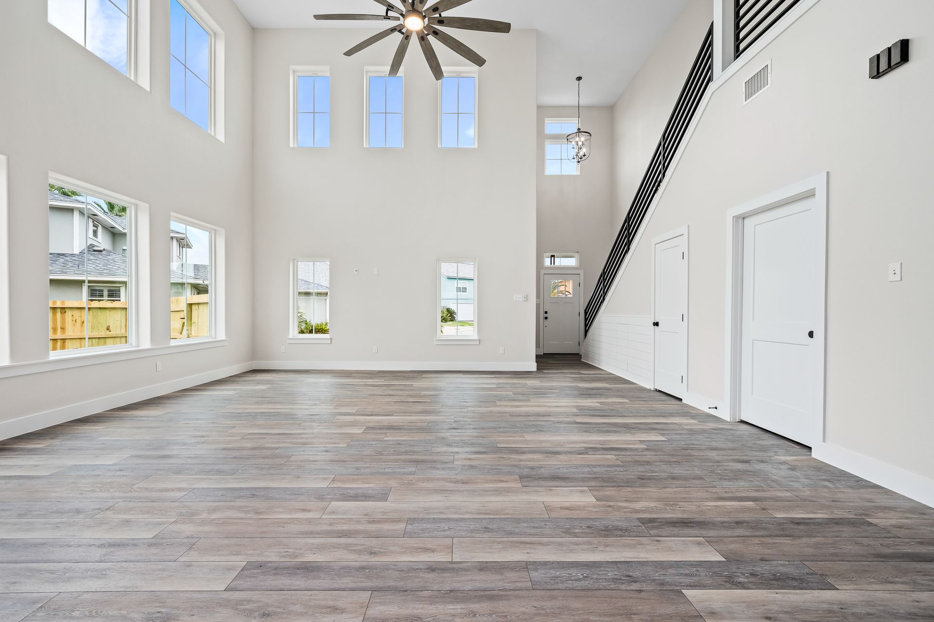 A large empty room with a wooden floor and a ceiling fan.