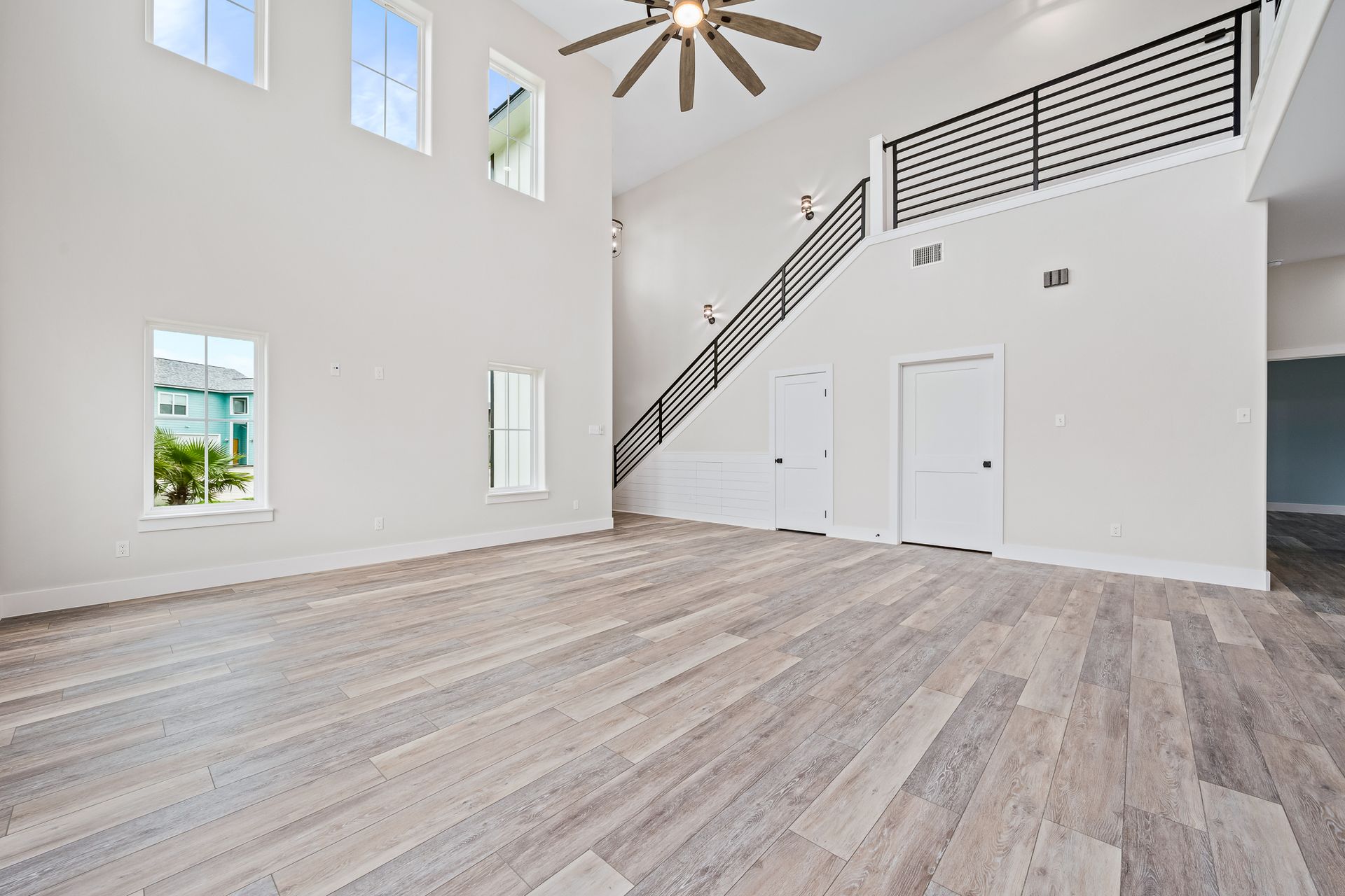 An empty living room with hardwood floors and a ceiling fan.