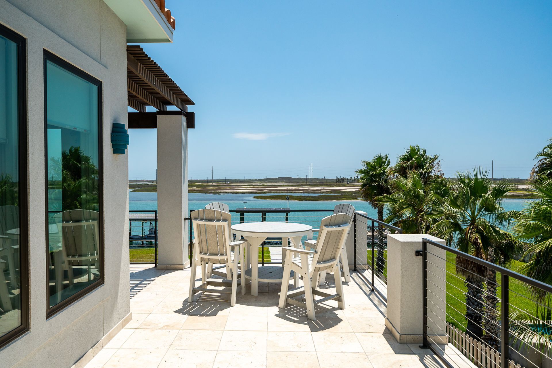 A balcony with a table and chairs overlooking a body of water