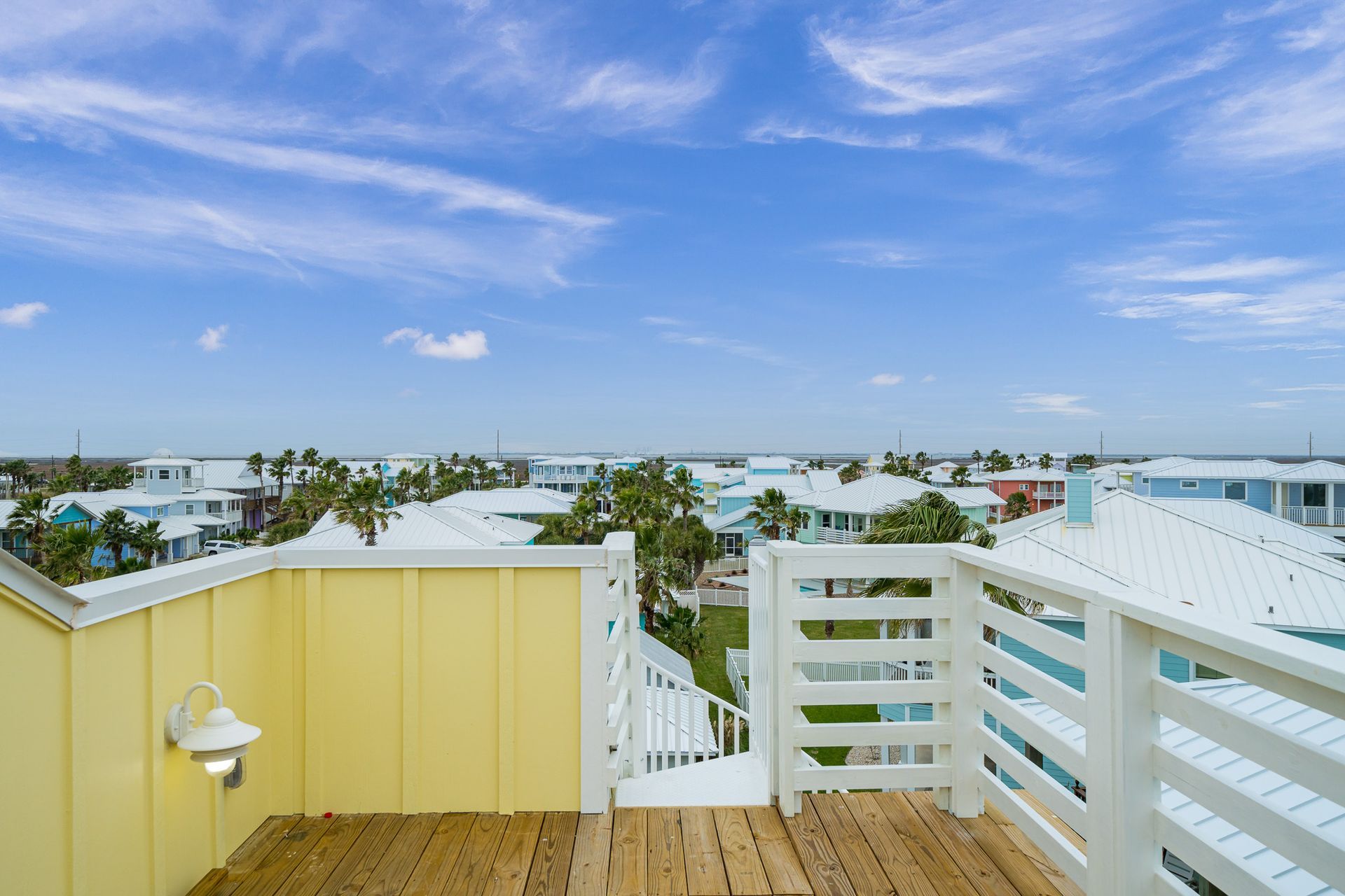 There is a balcony on the roof of a house with a view of the city.