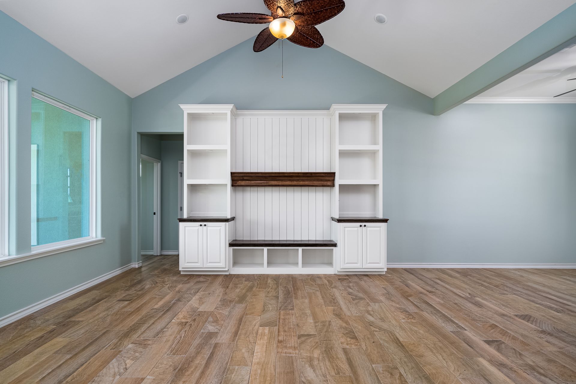 An empty living room with hardwood floors and a ceiling fan.