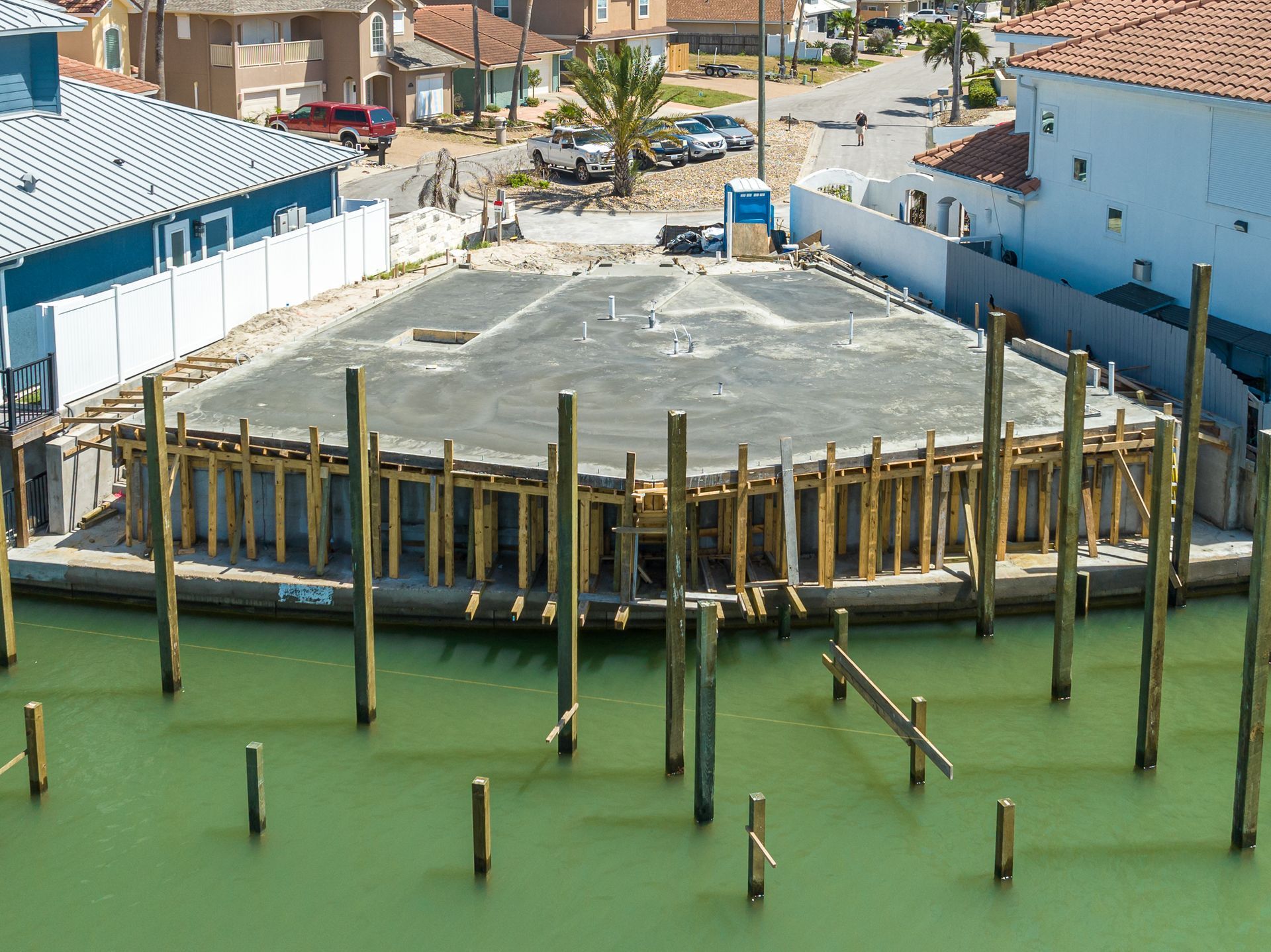 An aerial view of a construction site with a lot of wooden poles in the water.