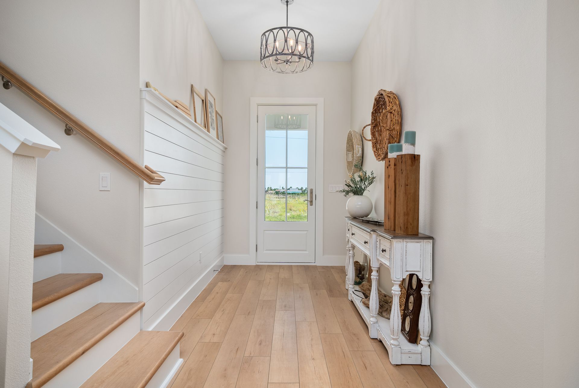 A hallway with wooden floors and stairs leading up to a door.