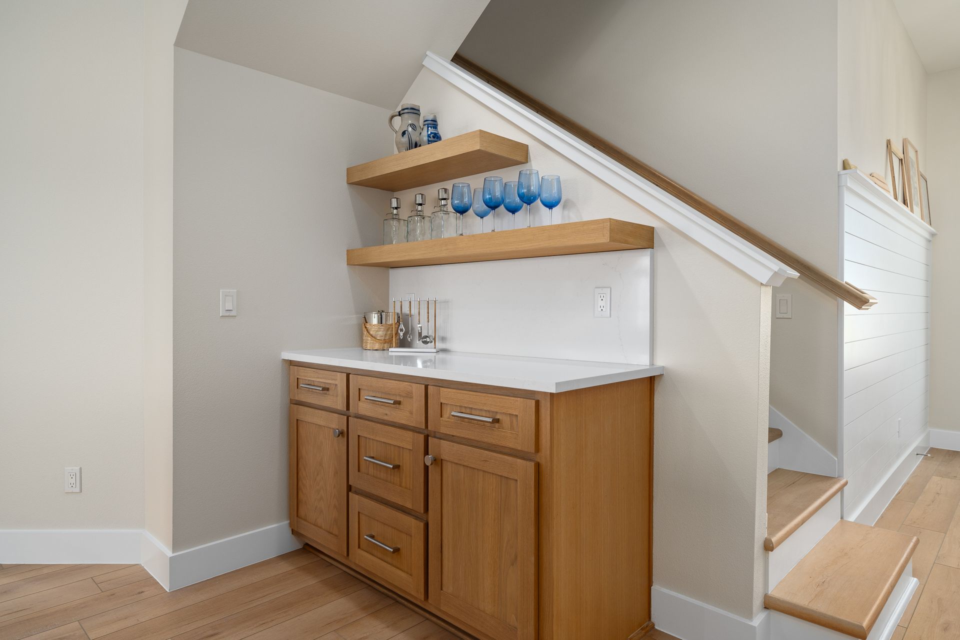 A kitchen with a bar under the stairs and a sink.