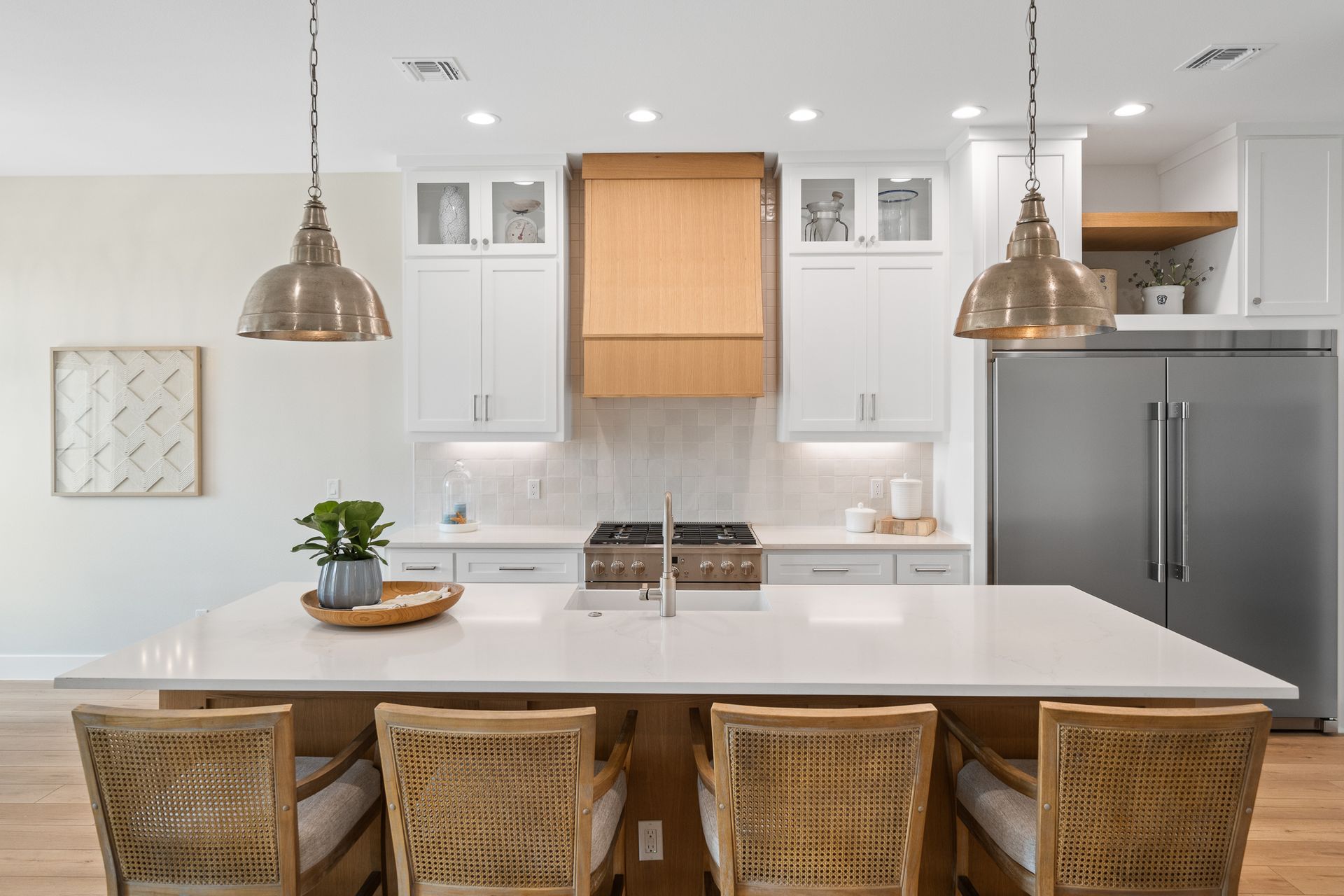 A kitchen with white cabinets , a large island , a stove and a refrigerator.