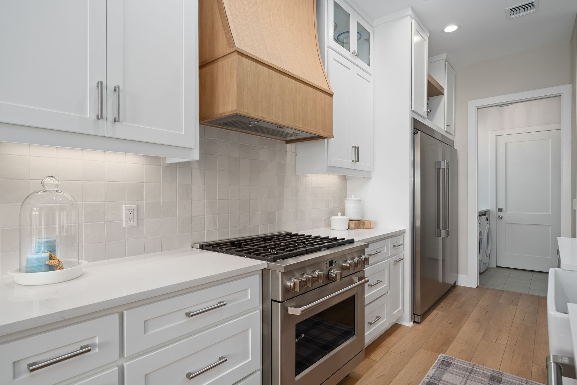 A kitchen with white cabinets , stainless steel appliances , a stove and a refrigerator.
