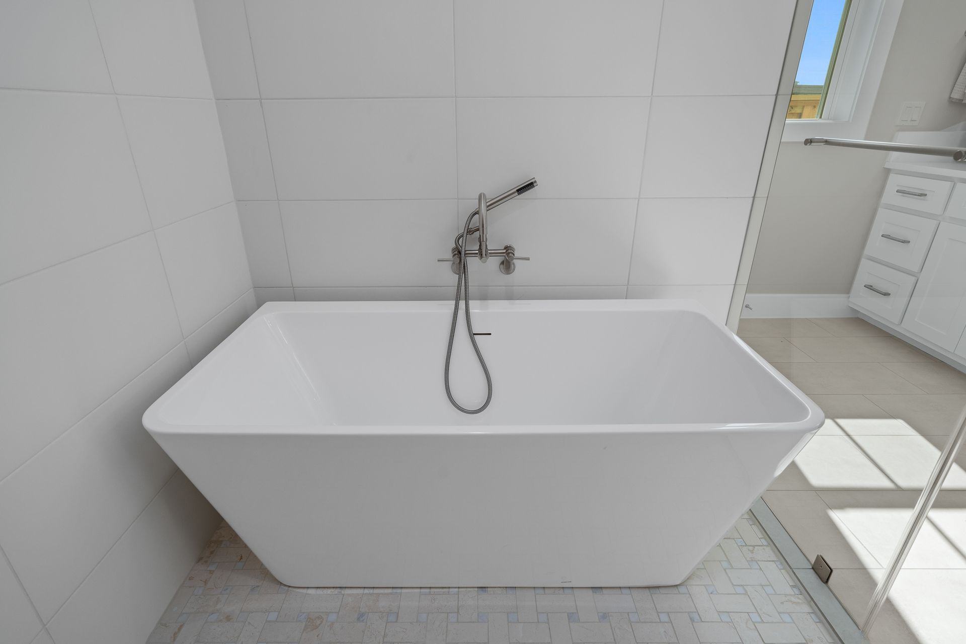 A white bathtub in a bathroom next to a mirror.