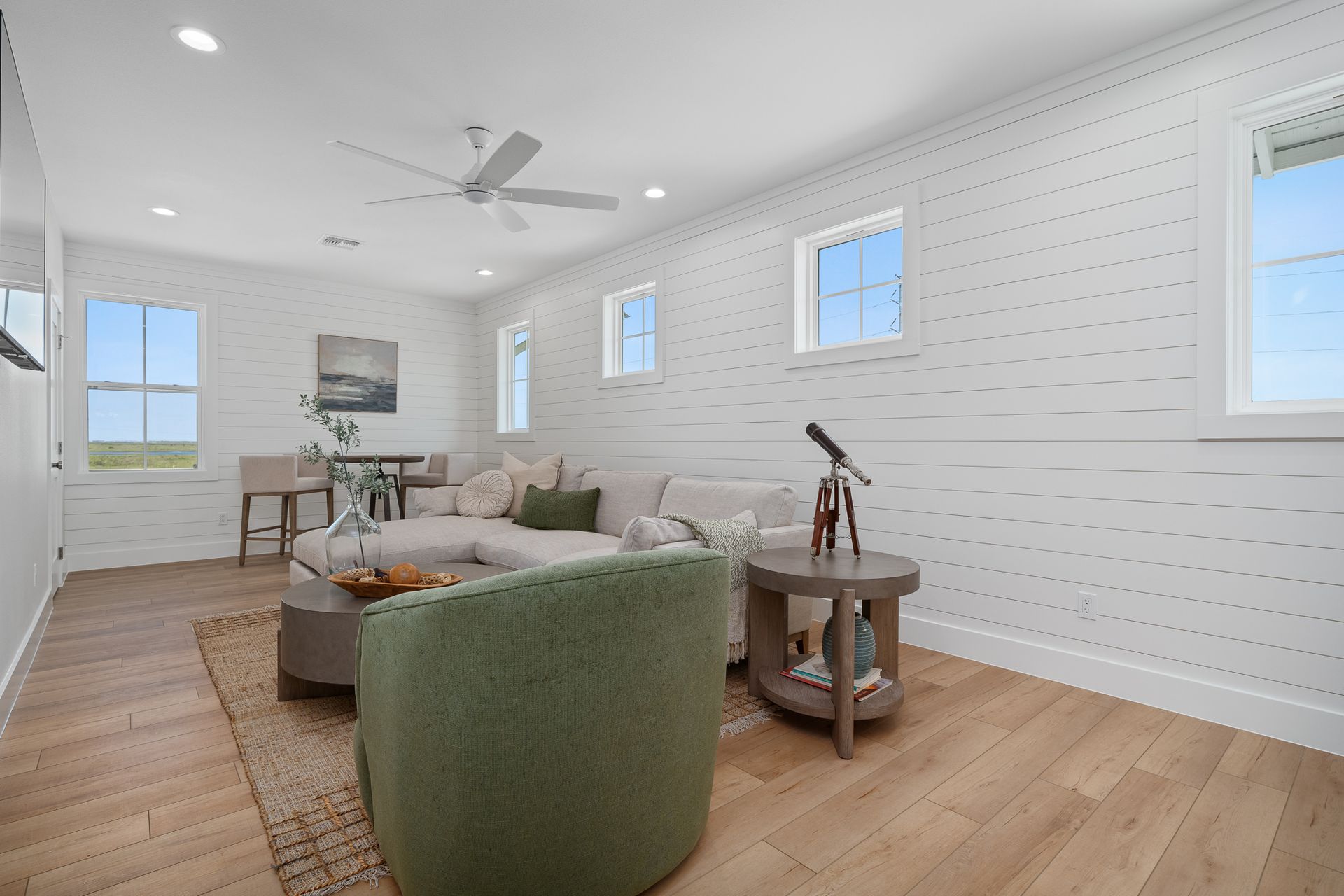 A living room with a couch , chair , table and ceiling fan.