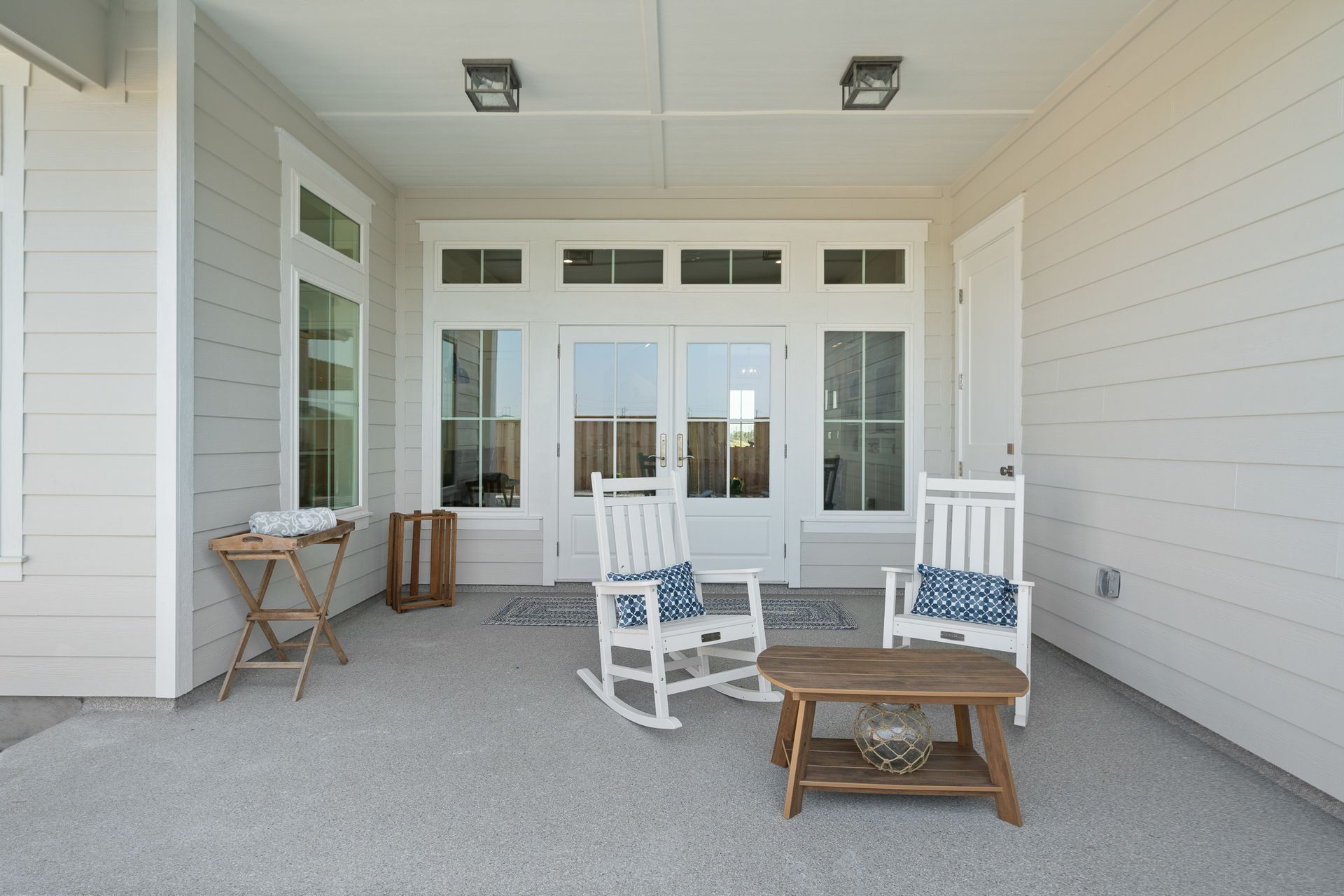 There are two rocking chairs and a table on the patio.