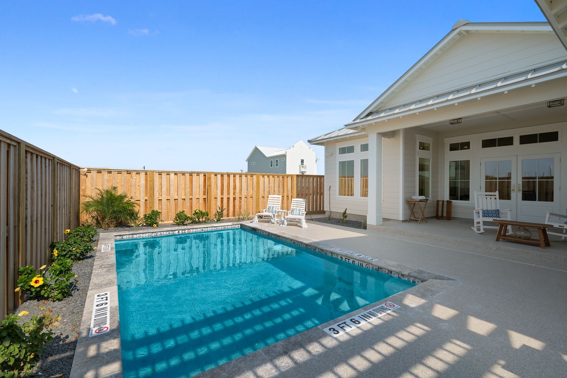 There is a large swimming pool in the backyard of a house.
