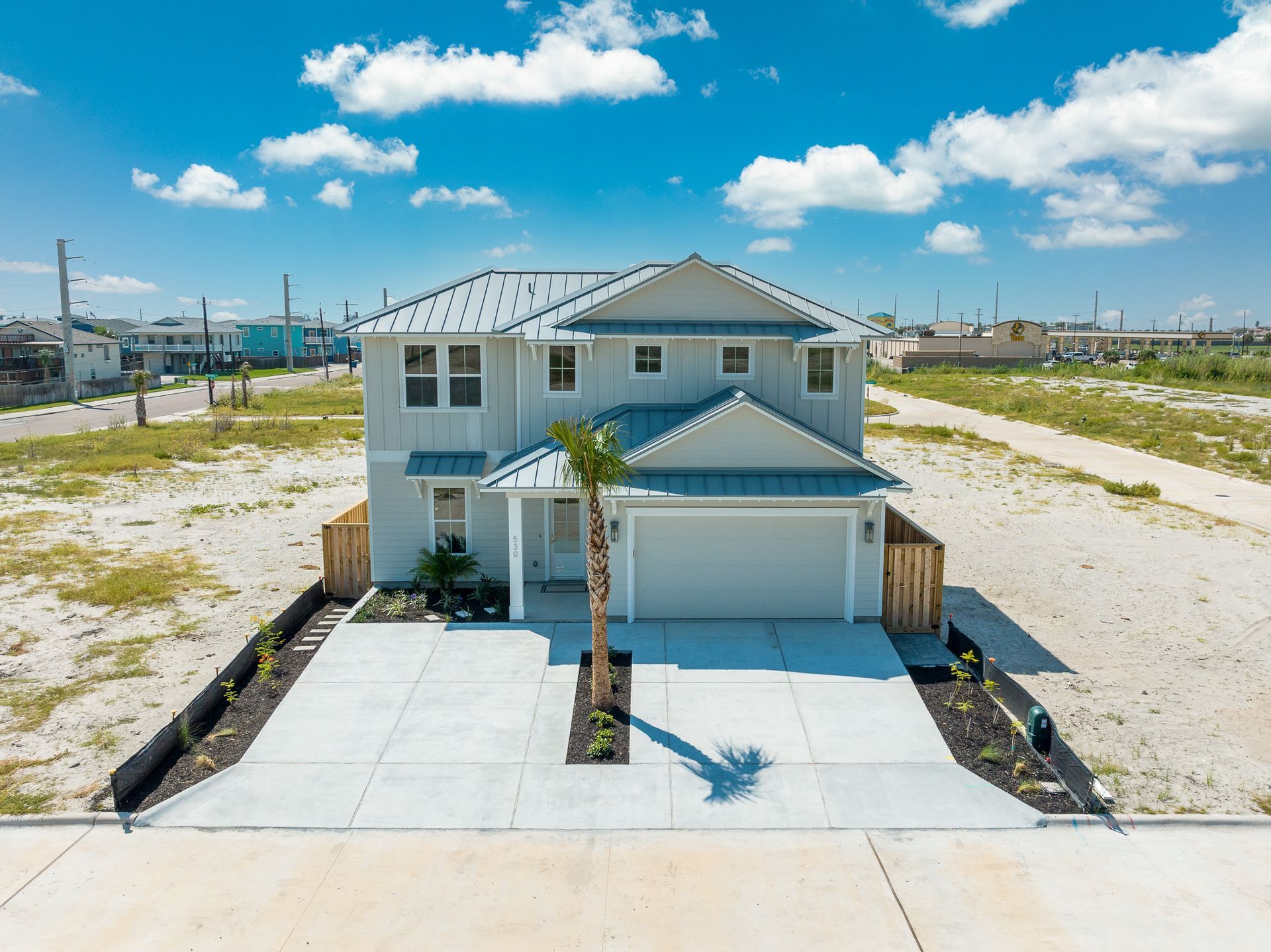 An aerial view of a white house with a palm tree in front of it.