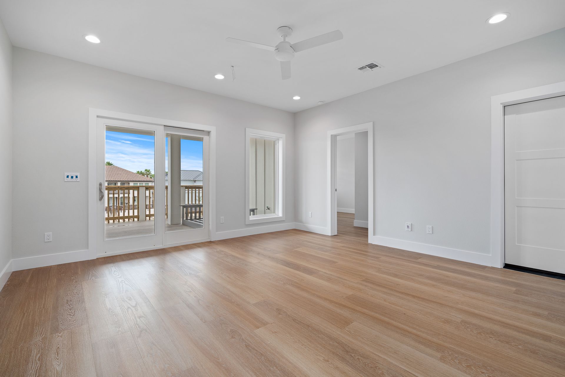 An empty living room with hardwood floors and a ceiling fan.