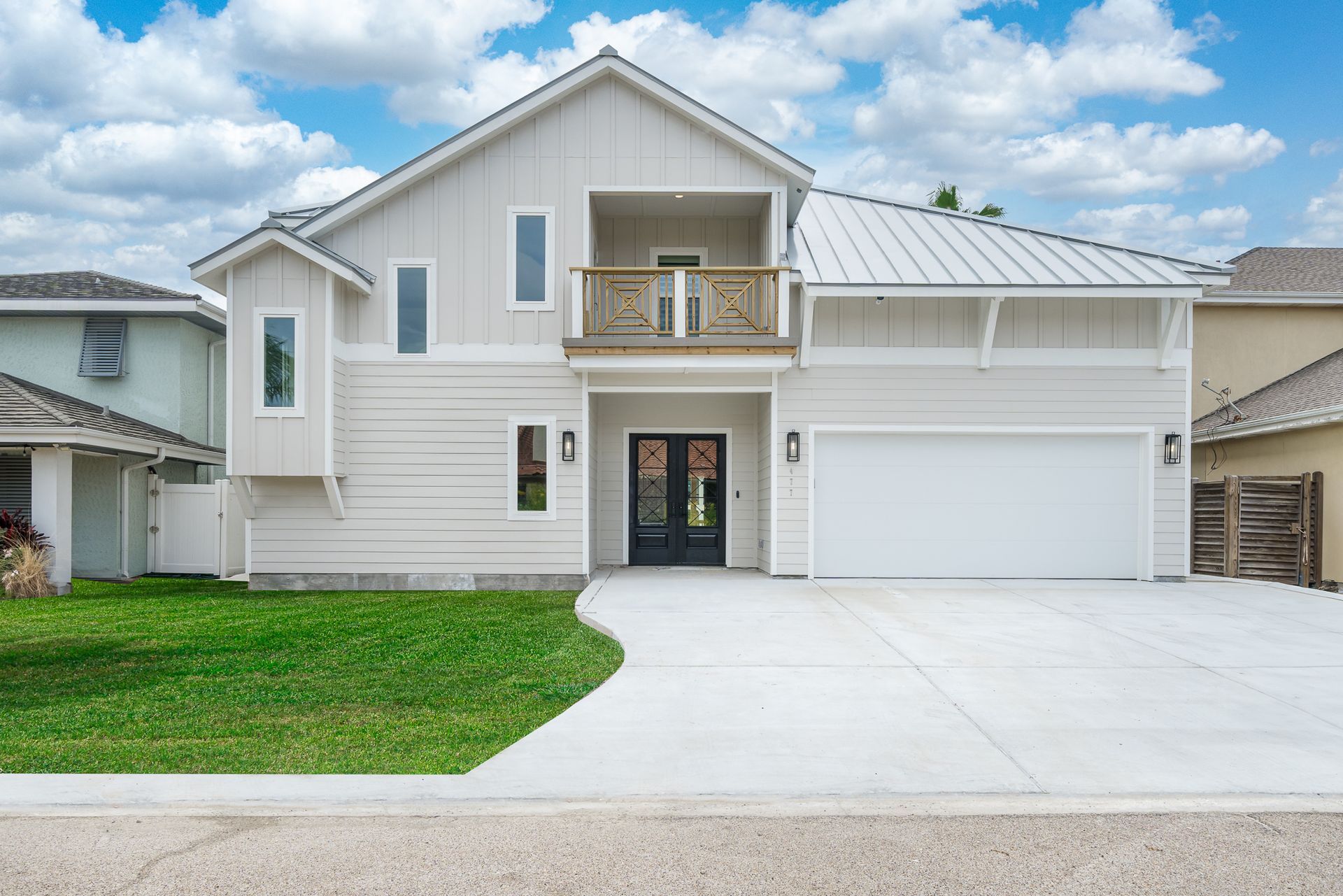 A large white house with a white garage door and a balcony.