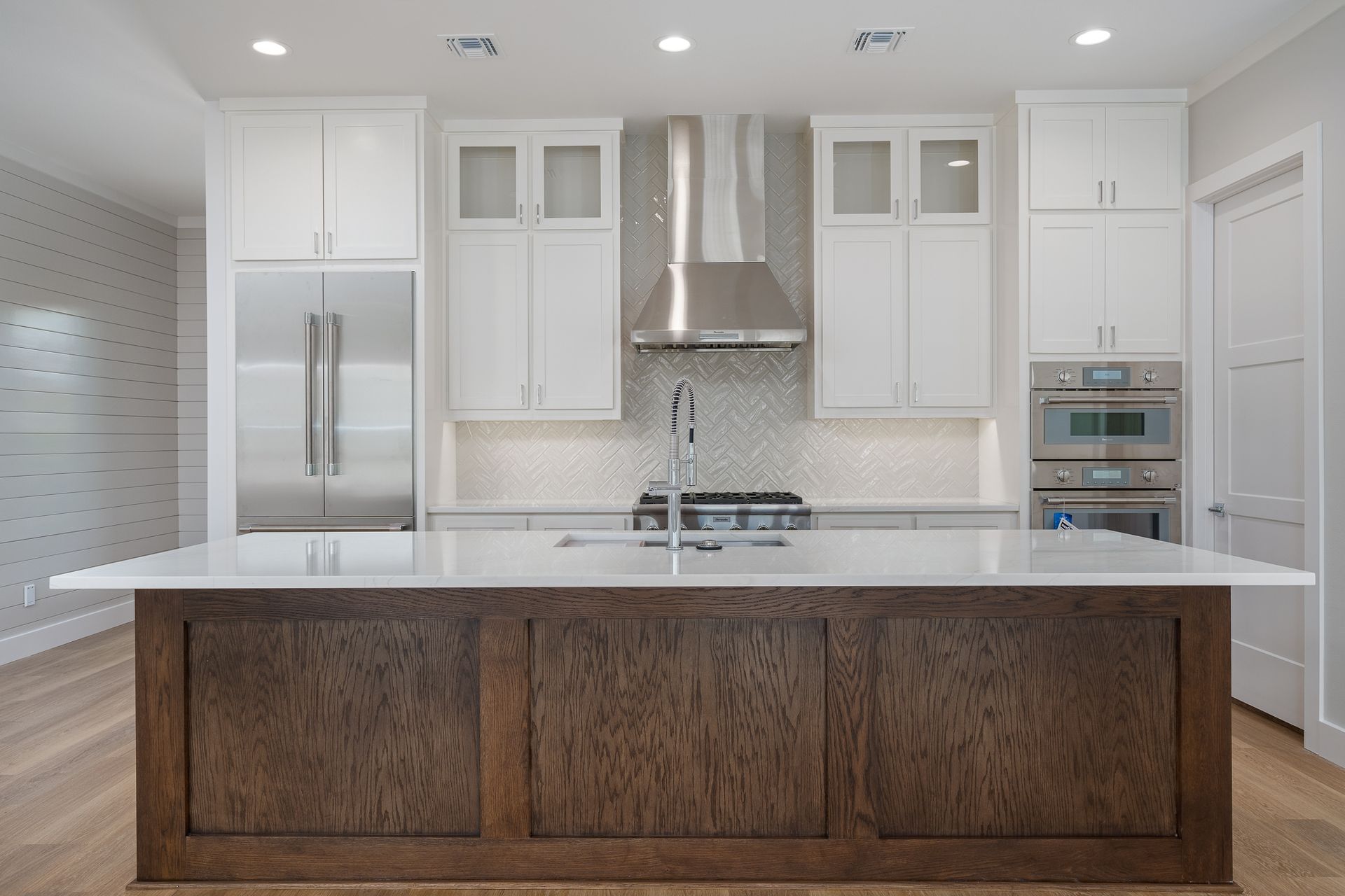 A kitchen with white cabinets , stainless steel appliances , and a large island.