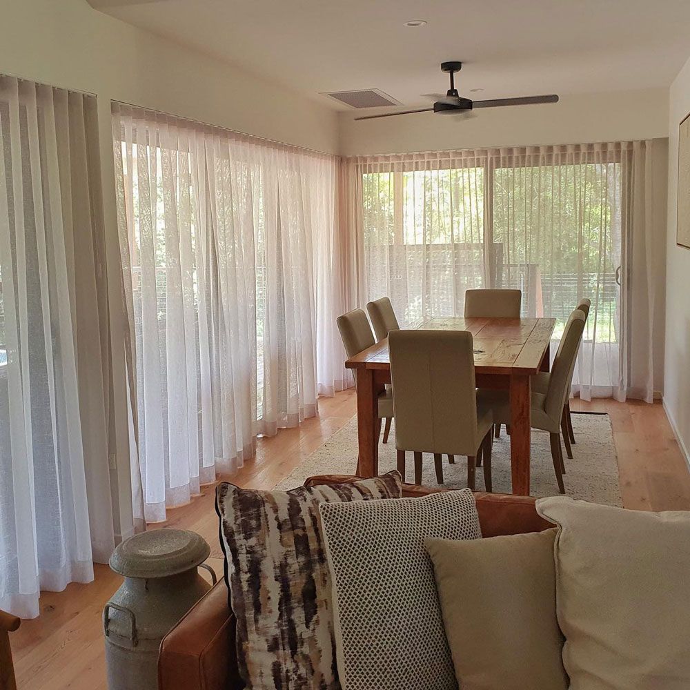 A Living Room With a Table and Chairs and a Ceiling Fan — Artizen Curtains in Mooloolaba, QLD