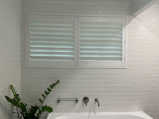 A Bathroom With a Tub and a Window With Shutters — Artizen Curtains in Mooloolaba, QLD