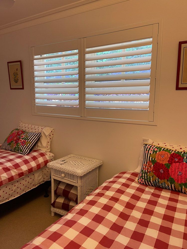 A Bedroom With Two Beds, a Nightstand, and a Window With Shutters — Artizen Curtains in Mooloolaba, QLD