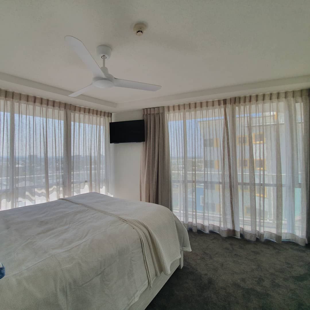A Bedroom With a Large Bed and a Ceiling Fan — Artizen Curtains in Mooloolaba, QLD