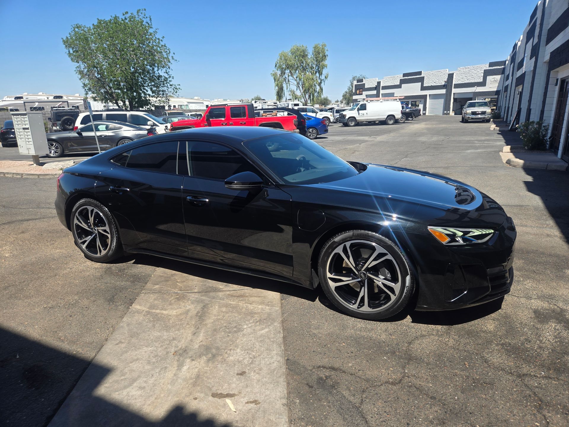 Black luxury sedan with freshly applied ceramic coating parked outside detailing shop in Gilbert AZ