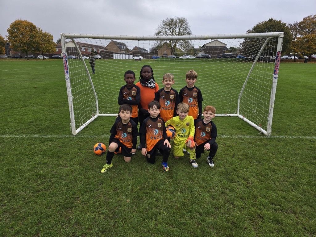 A group of young boys are posing for a picture on a soccer field.