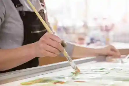 A person is painting with a brush on a piece of paper.