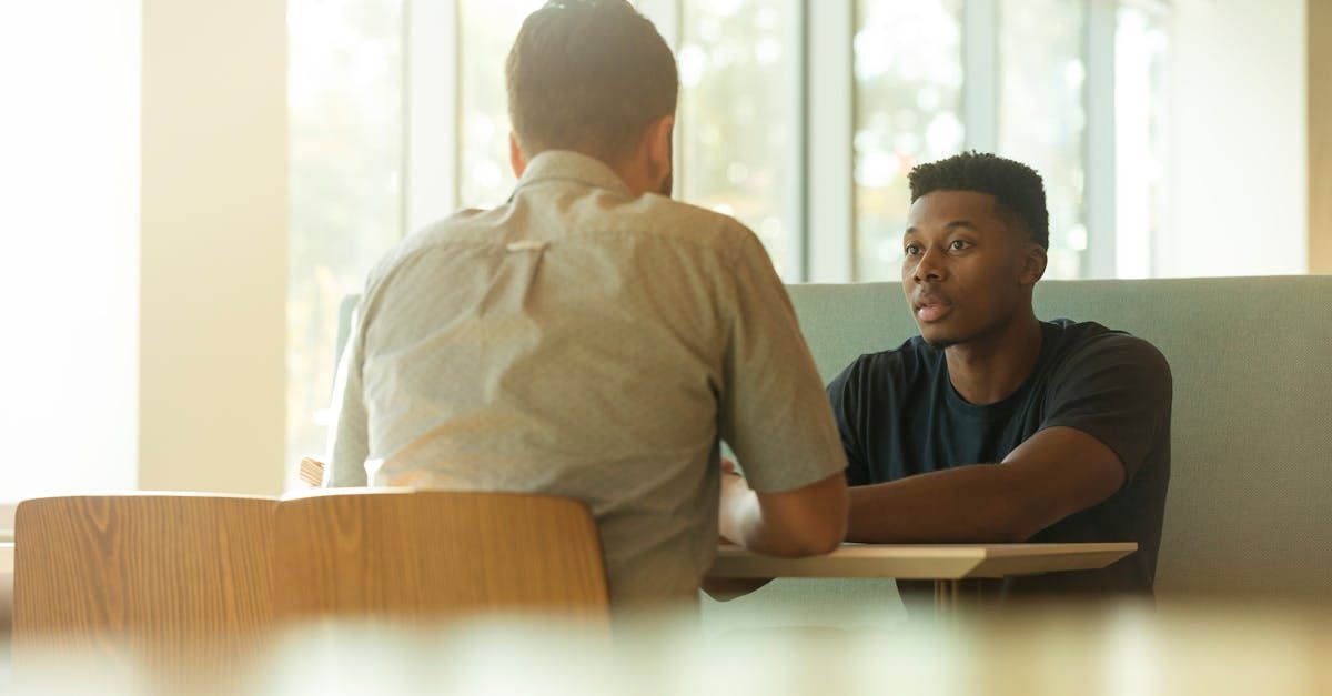 Two men are sitting at a table having a conversation.