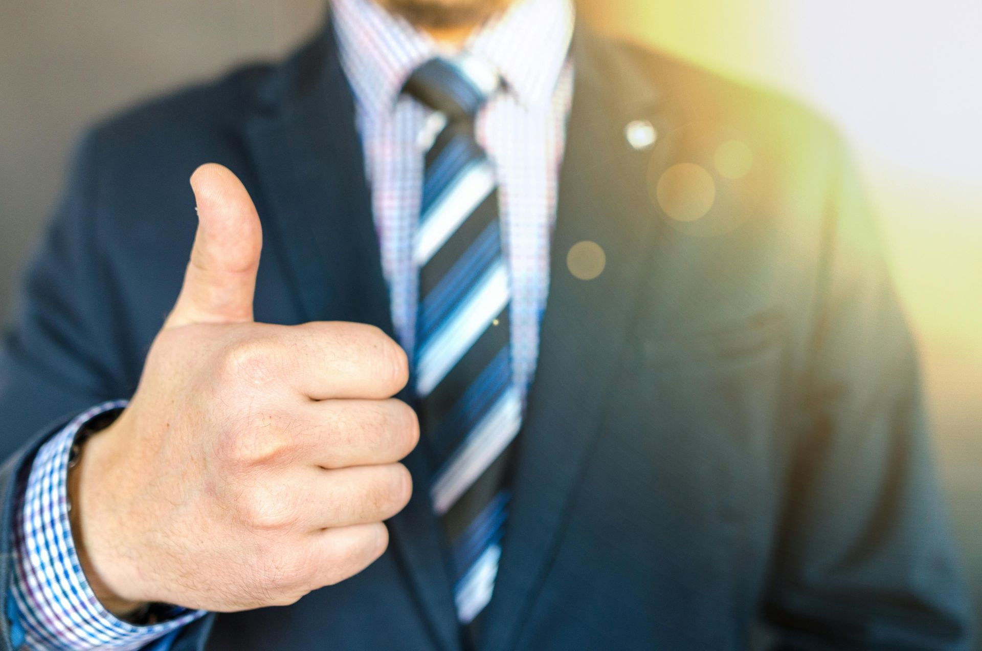 A man in a suit and tie is giving a thumbs up.