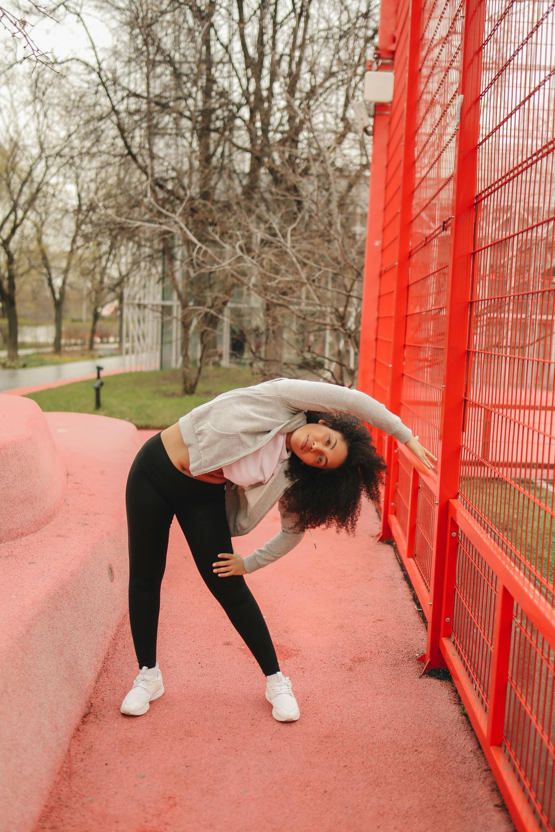 A woman is bending over in front of a red fence.